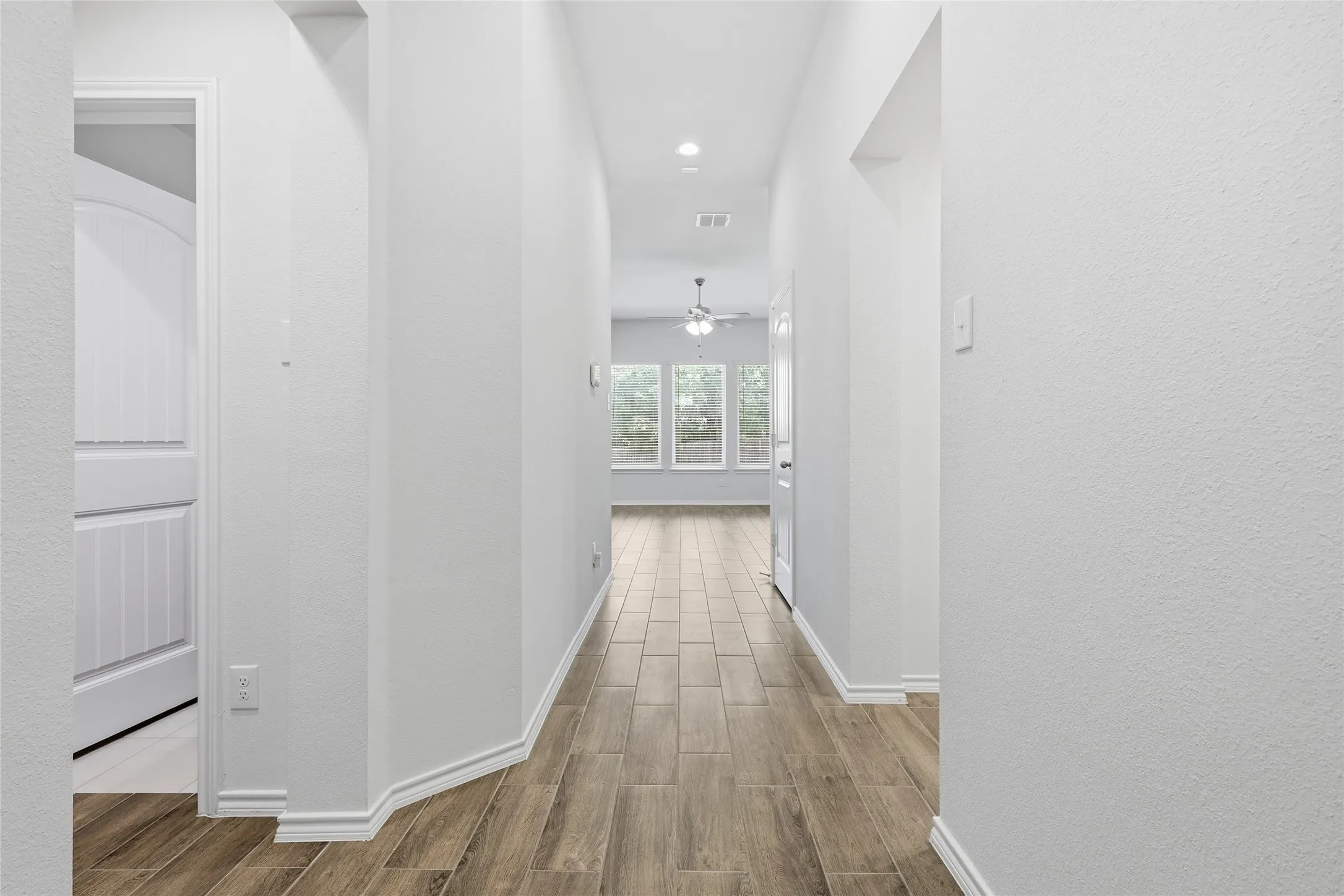 Hallway featuring wood-finish tile flooring, recessed lighting, and white baseboards