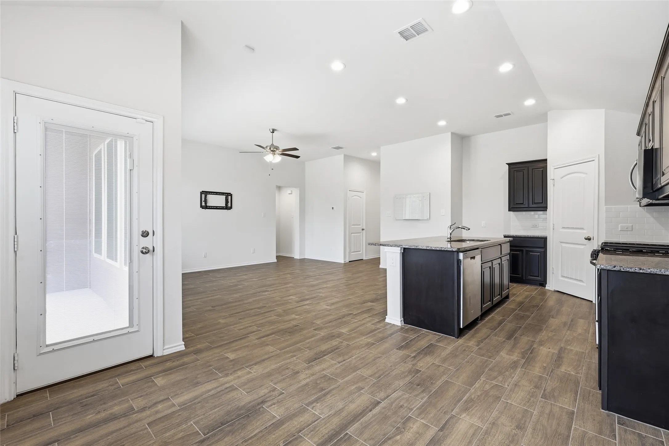 Open-concept kitchen and living area featuring wood-finish flooring, recessed lighting, and a ceiling fan