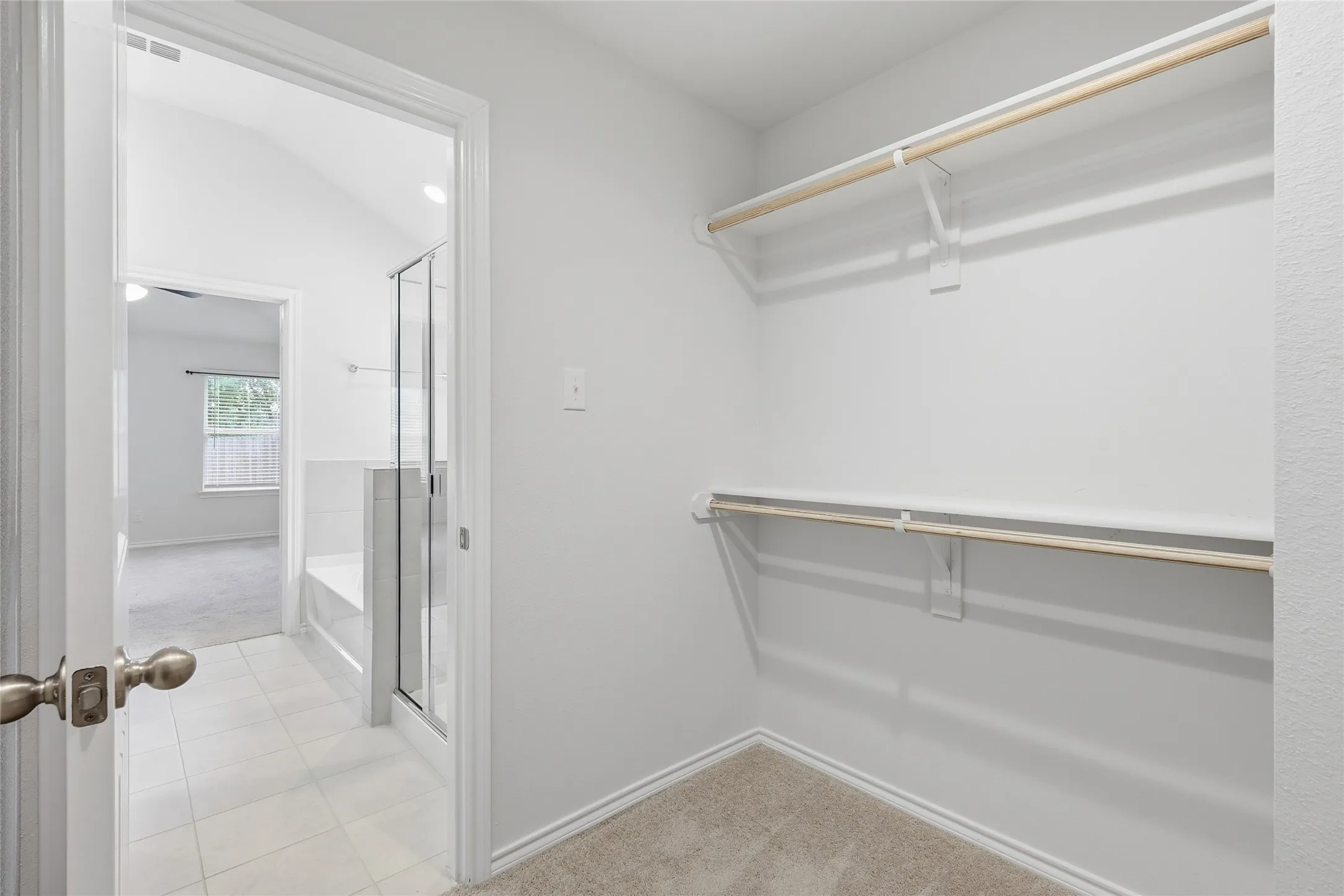 Walk-in closet with carpet flooring, upper and lower shelving, and hanging rods