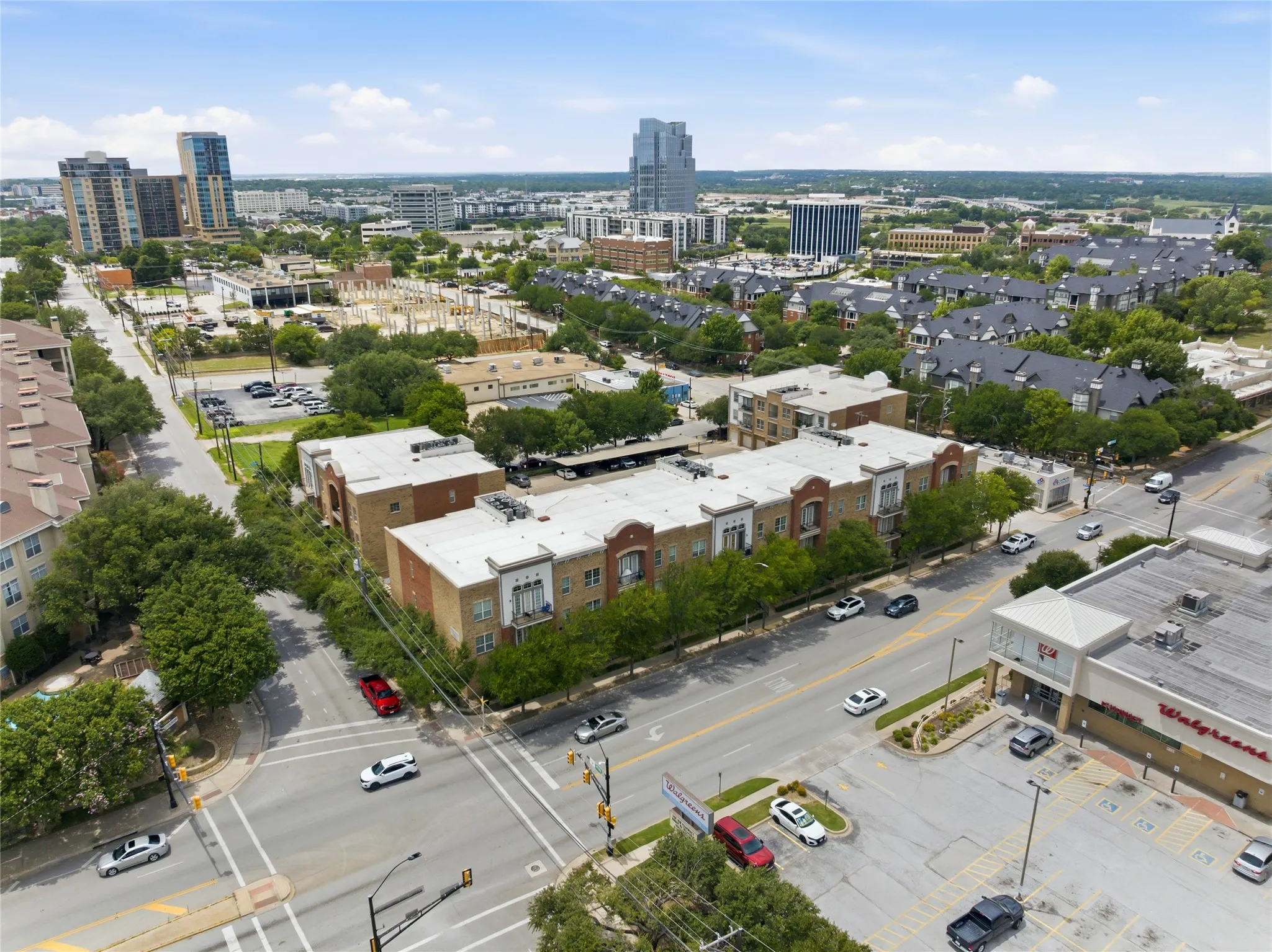 Multi-story residential buildings featuring brick and stucco exteriors, visible street access, and established surrounding greenery