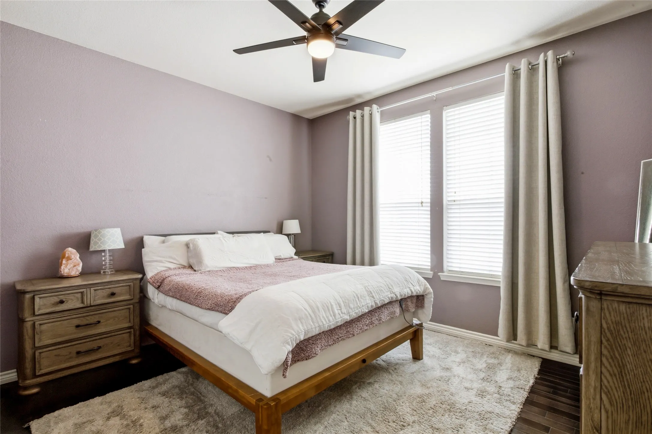 Bedroom featuring windows with horizontal blinds, a ceiling fan with integrated lighting, wood-finish flooring, and light-colored walls
