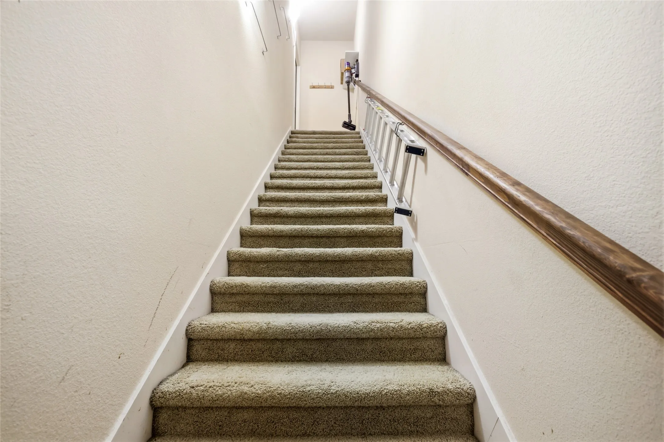 Private Entrance from the garage up the carpeted staircase with a wood handrail