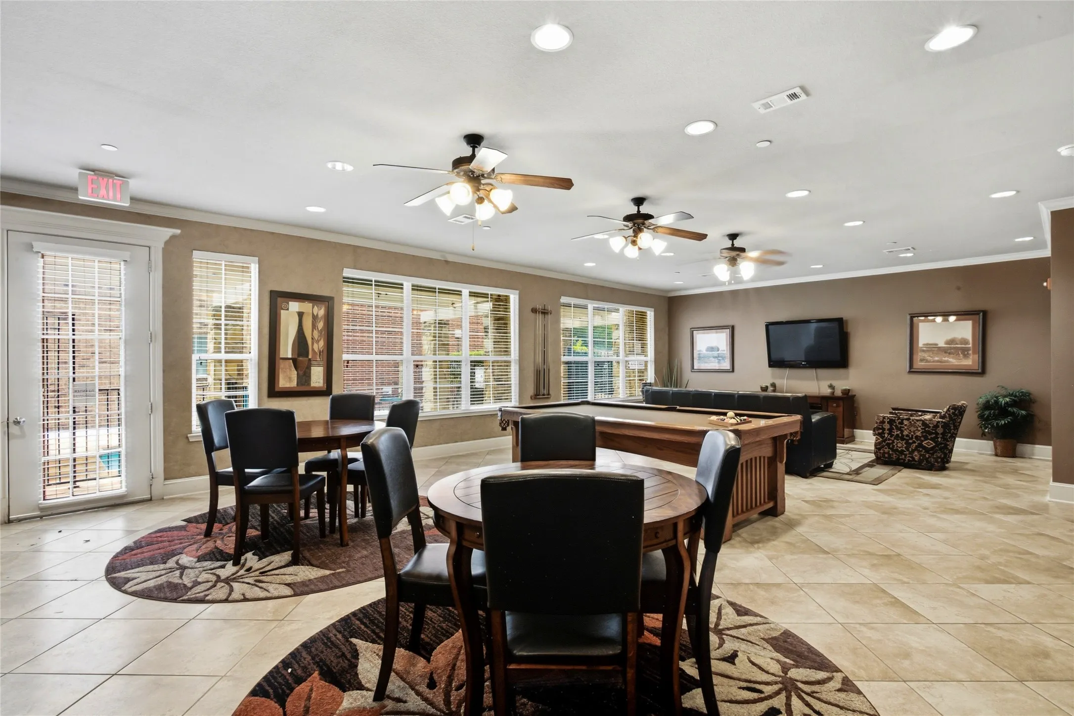 Spacious common area featuring tile flooring, multiple ceiling fans, recessed lighting, and large windows providing abundant natural light