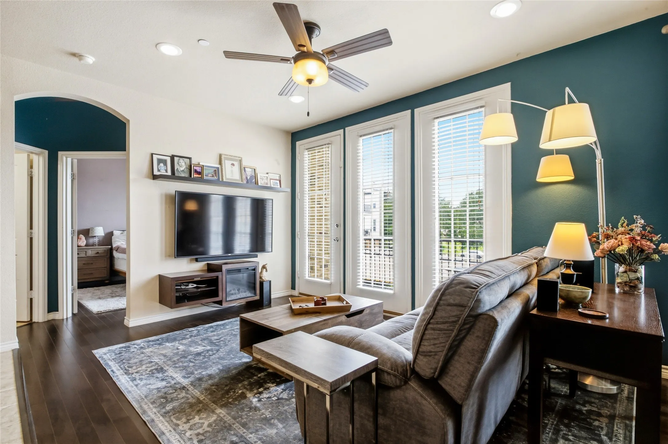 Different view of your new living area featuring dark wood-finish flooring, a ceiling fan with integrated lighting, recessed lighting, and a prominent accent wall