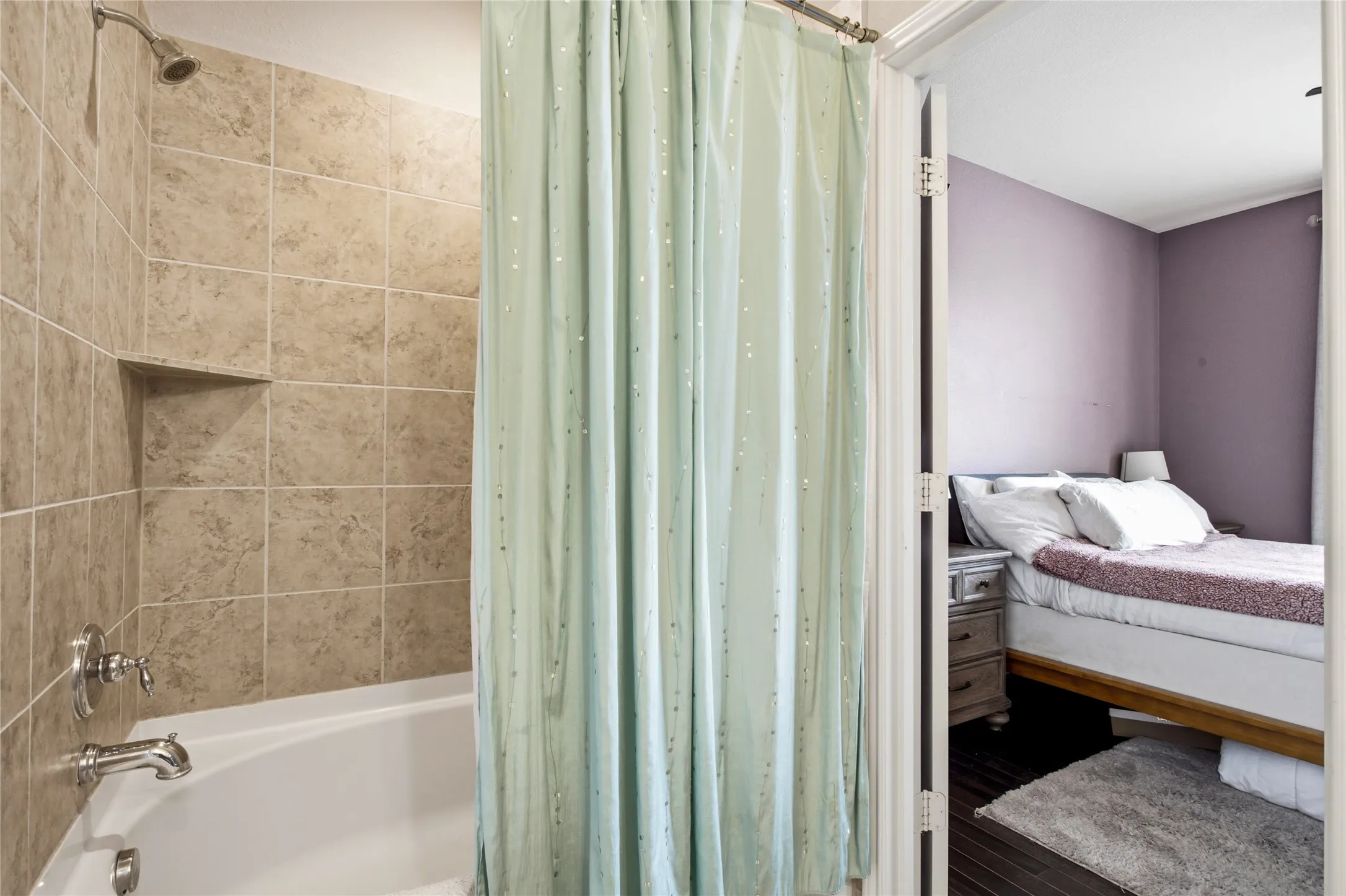 Bathtub with tiled surround, integrated shower niche, and chrome fixtures