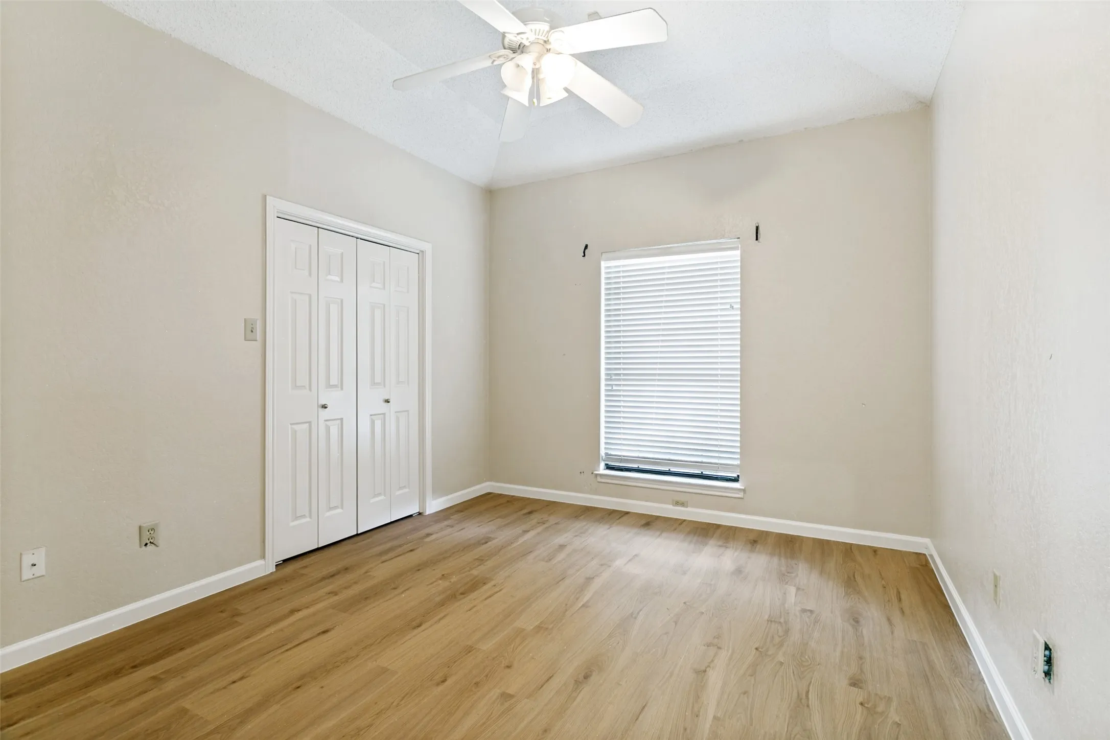 Bedroom featuring vaulted ceilings, wood-finish flooring, a ceiling fan, a window with horizontal blinds, and a bi-fold closet