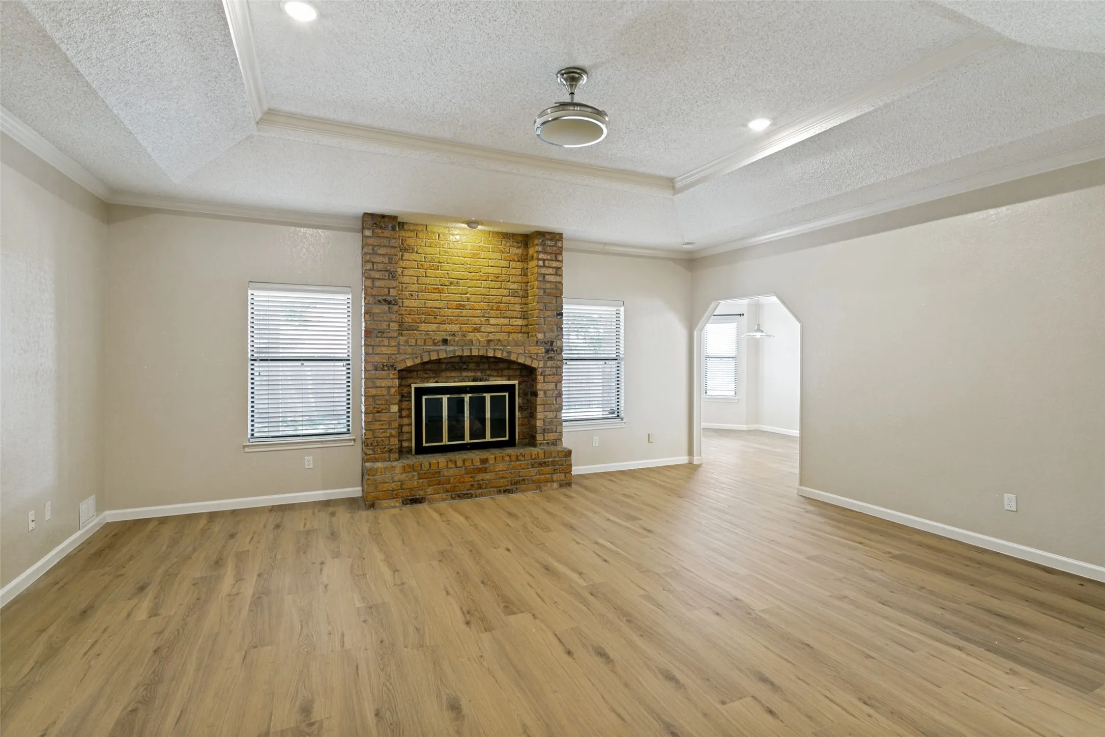 Living area featuring a brick-faced fireplace, wood-finish flooring, and recessed lighting
