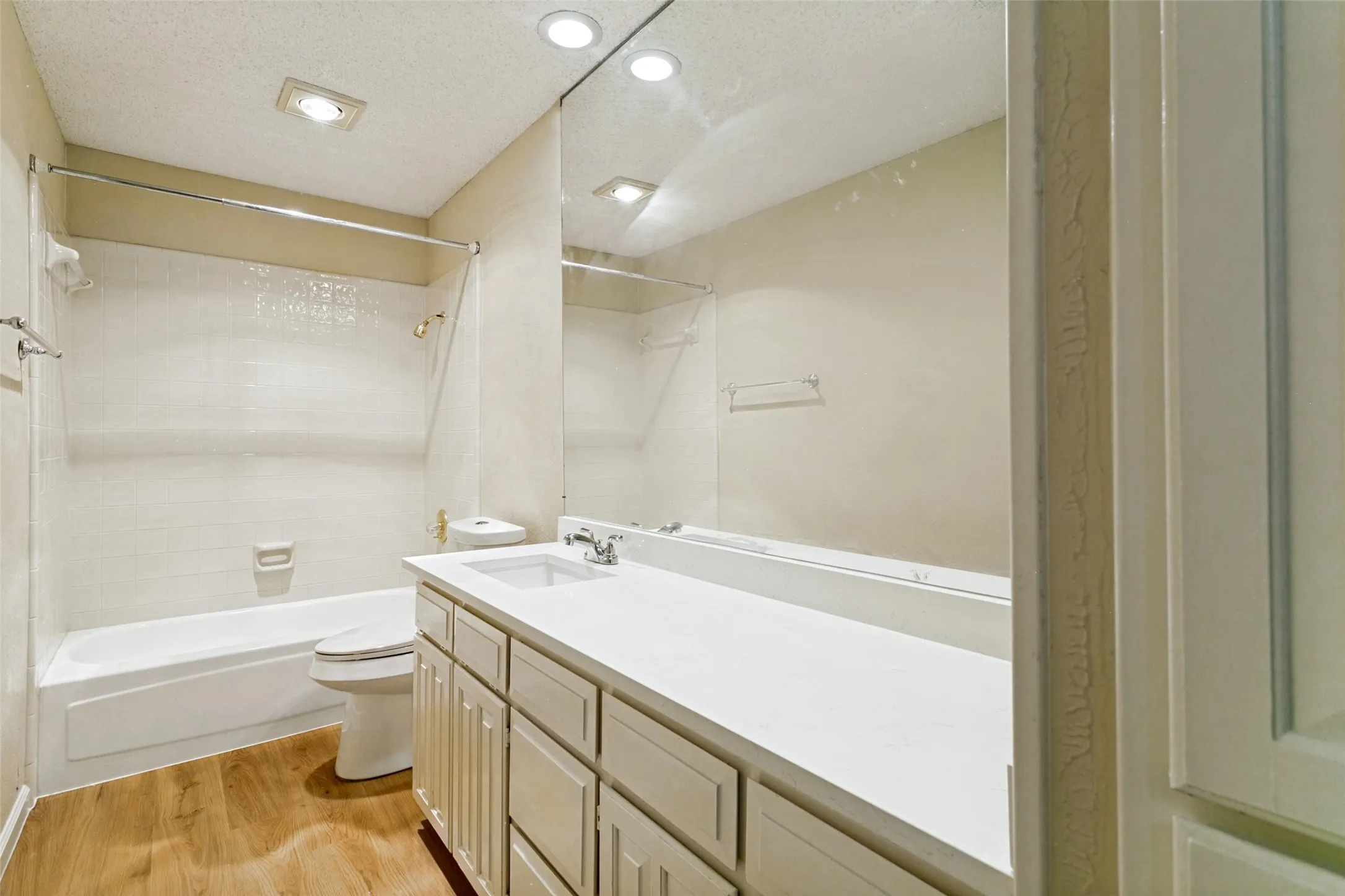 Bathroom featuring a spacious vanity with integrated sink, a large mirror, recessed lighting, and wood-finish flooring