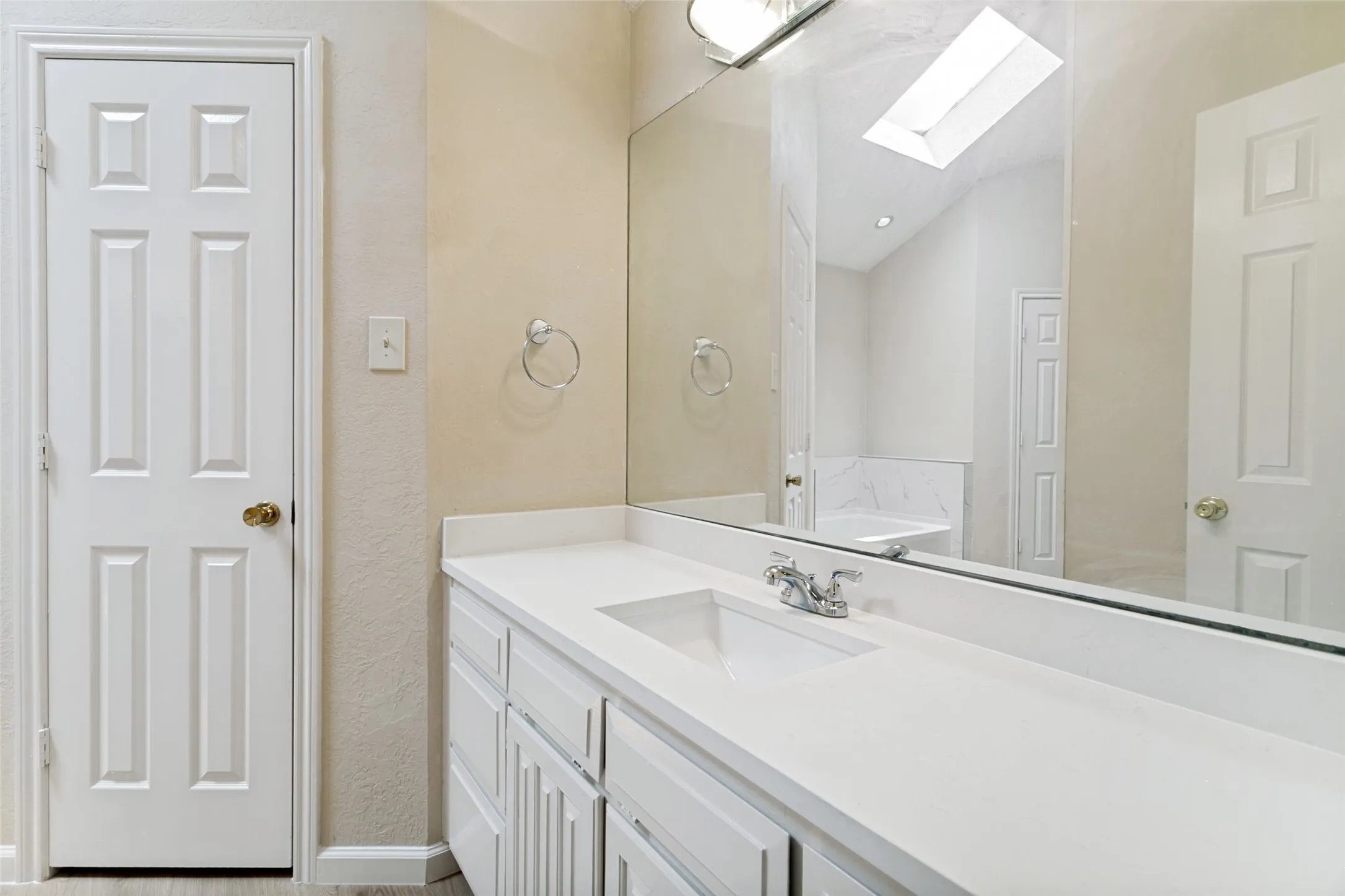 Bathroom vanity featuring white cabinetry, a single basin sink, and chrome fixtures