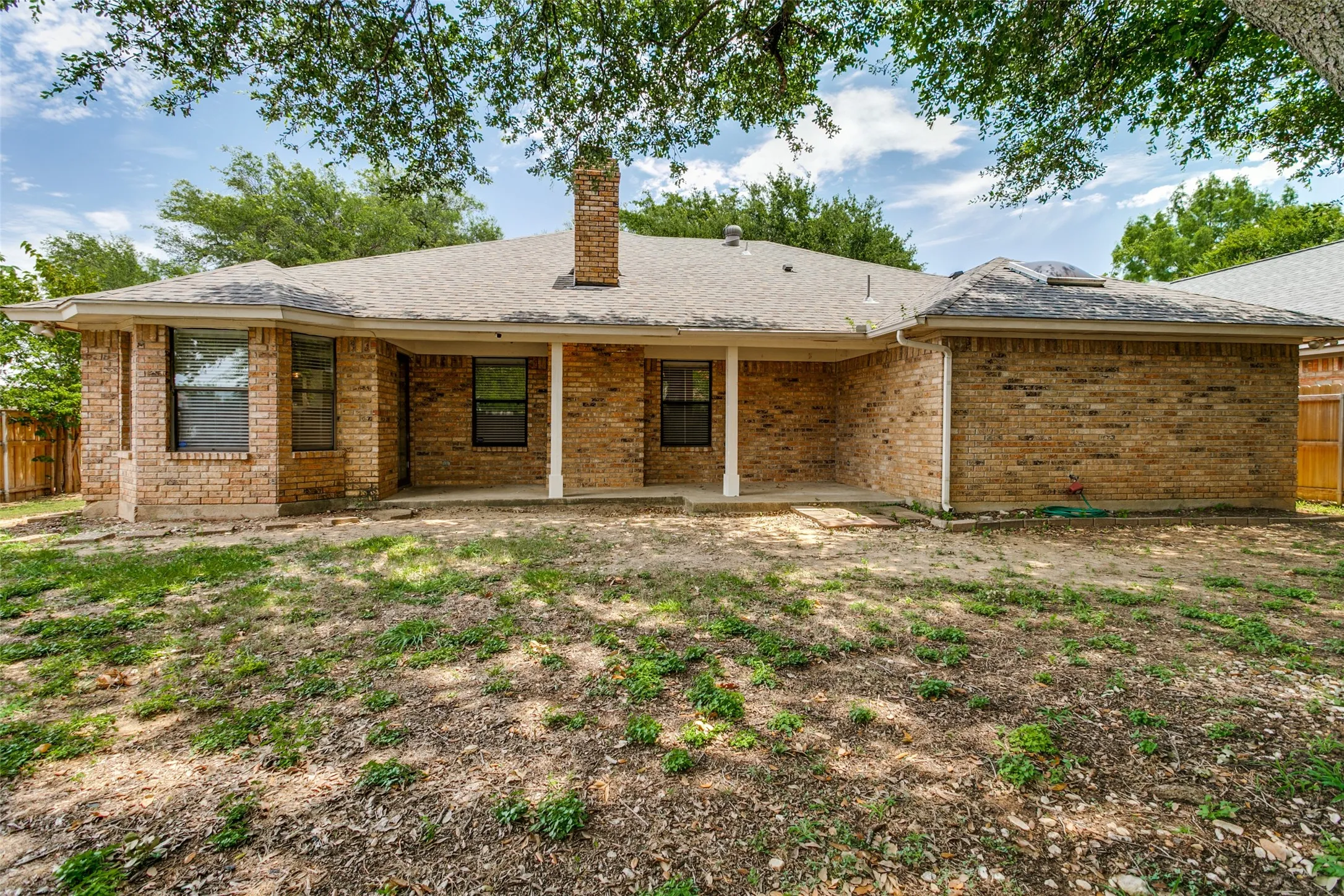 Brick exterior with a covered patio and multiple windows
