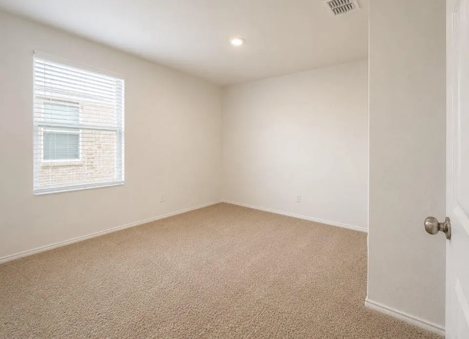 Spacious room featuring neutral carpeting, a large window with horizontal blinds, and recessed lighting