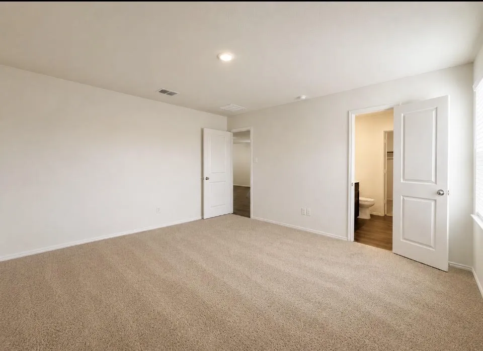 Spacious room featuring neutral carpeting, light-colored walls, recessed lighting, and a window with horizontal blinds