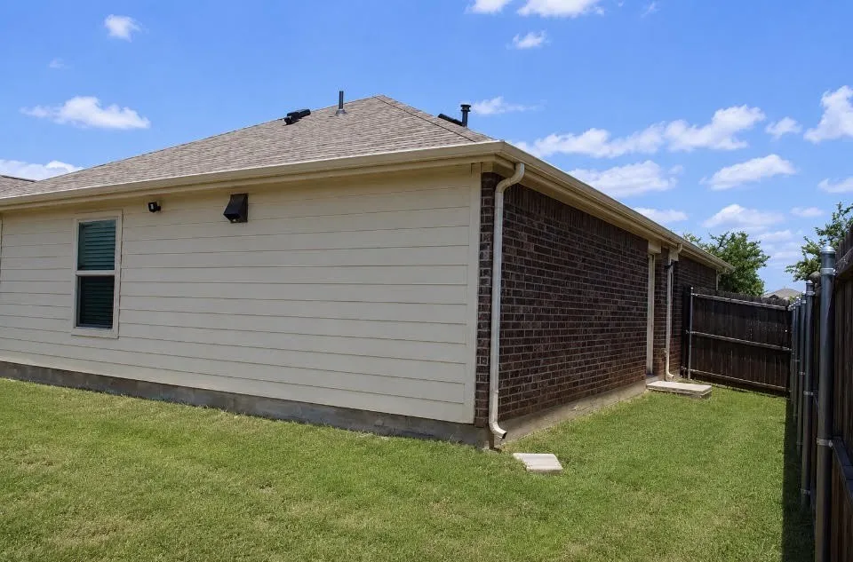 Exterior featuring brick and horizontal siding, a shingled roof, and white gutters