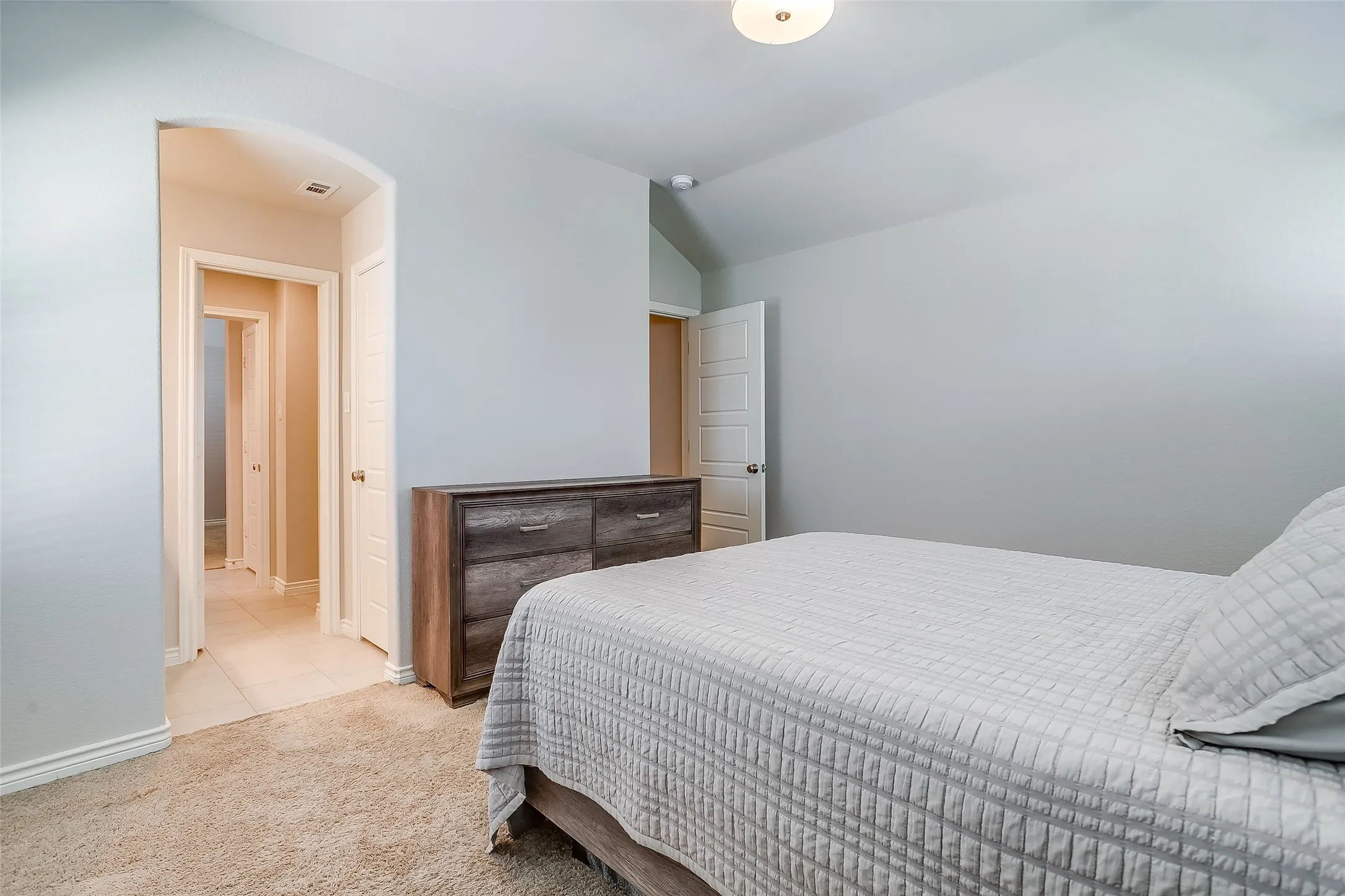 Carpeted room featuring light-colored walls and a vaulted ceiling