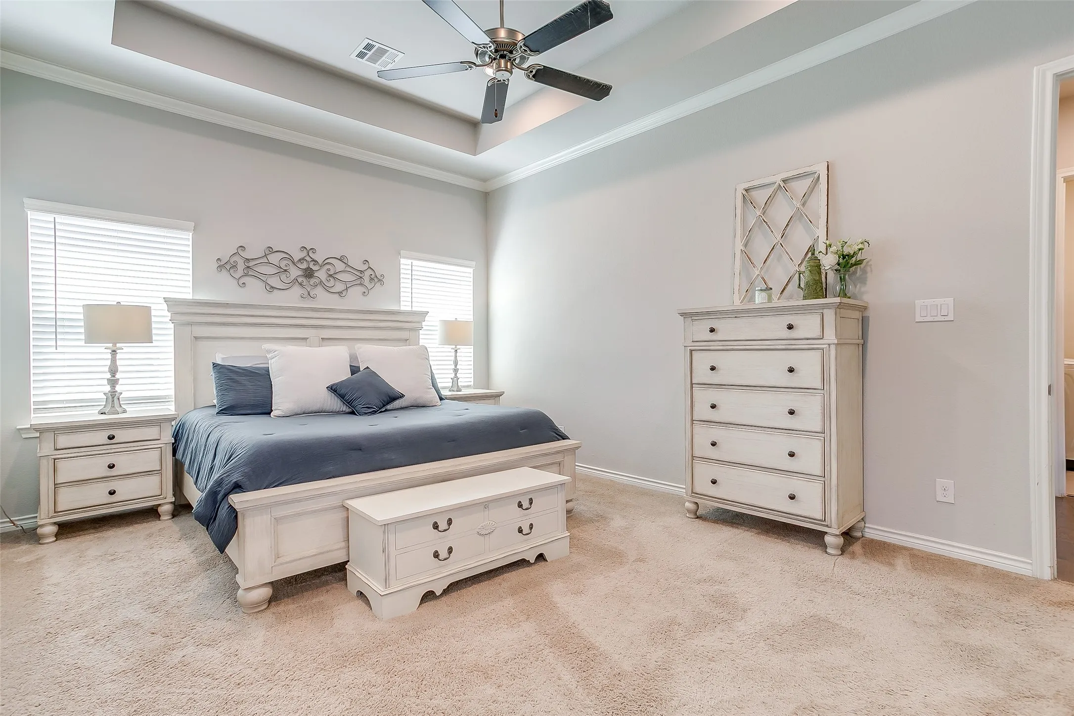 Carpeted room featuring a tray ceiling, ceiling fan, and white baseboards