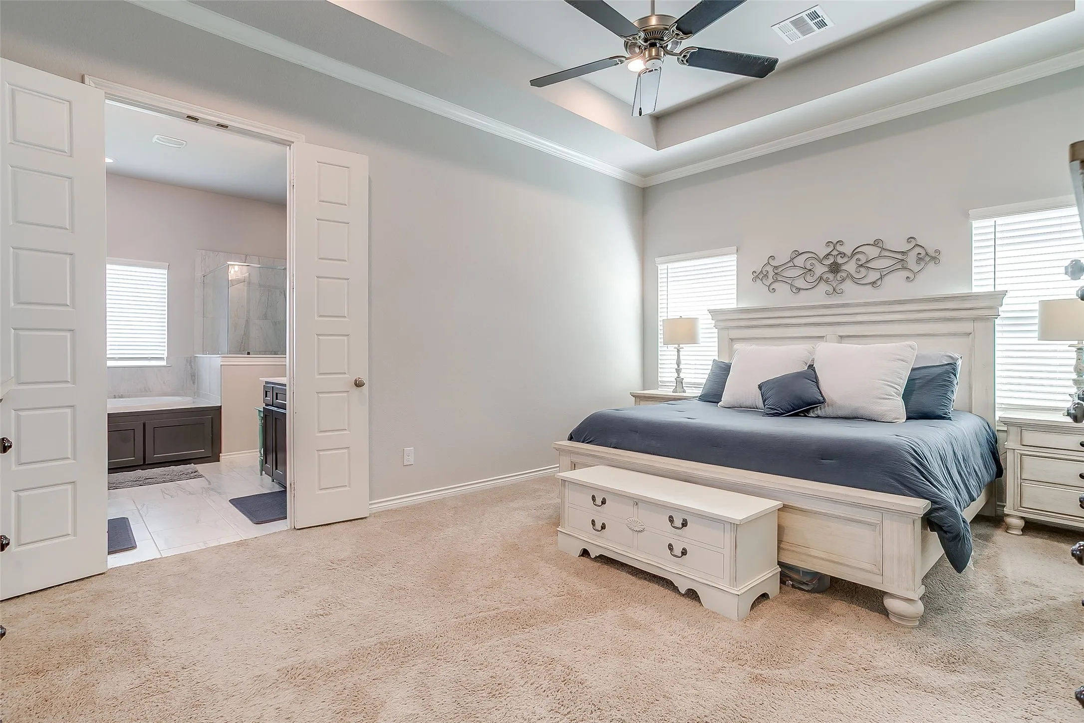 Spacious bedroom featuring a tray ceiling, recessed lighting, and a ceiling fan