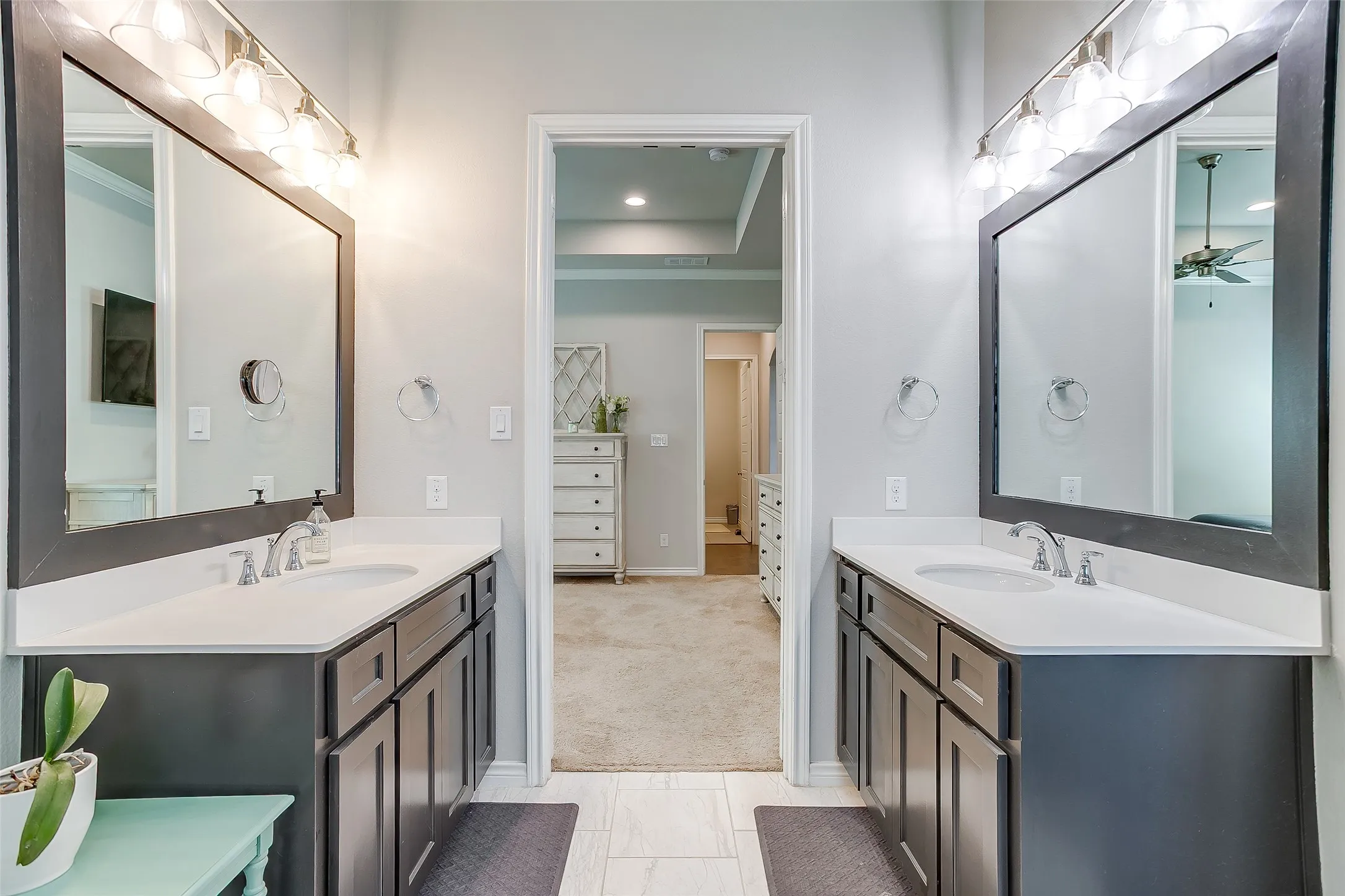 Double vanity bathroom featuring white countertops, undermount sinks, chrome faucets, framed mirrors, and overhead light fixtures