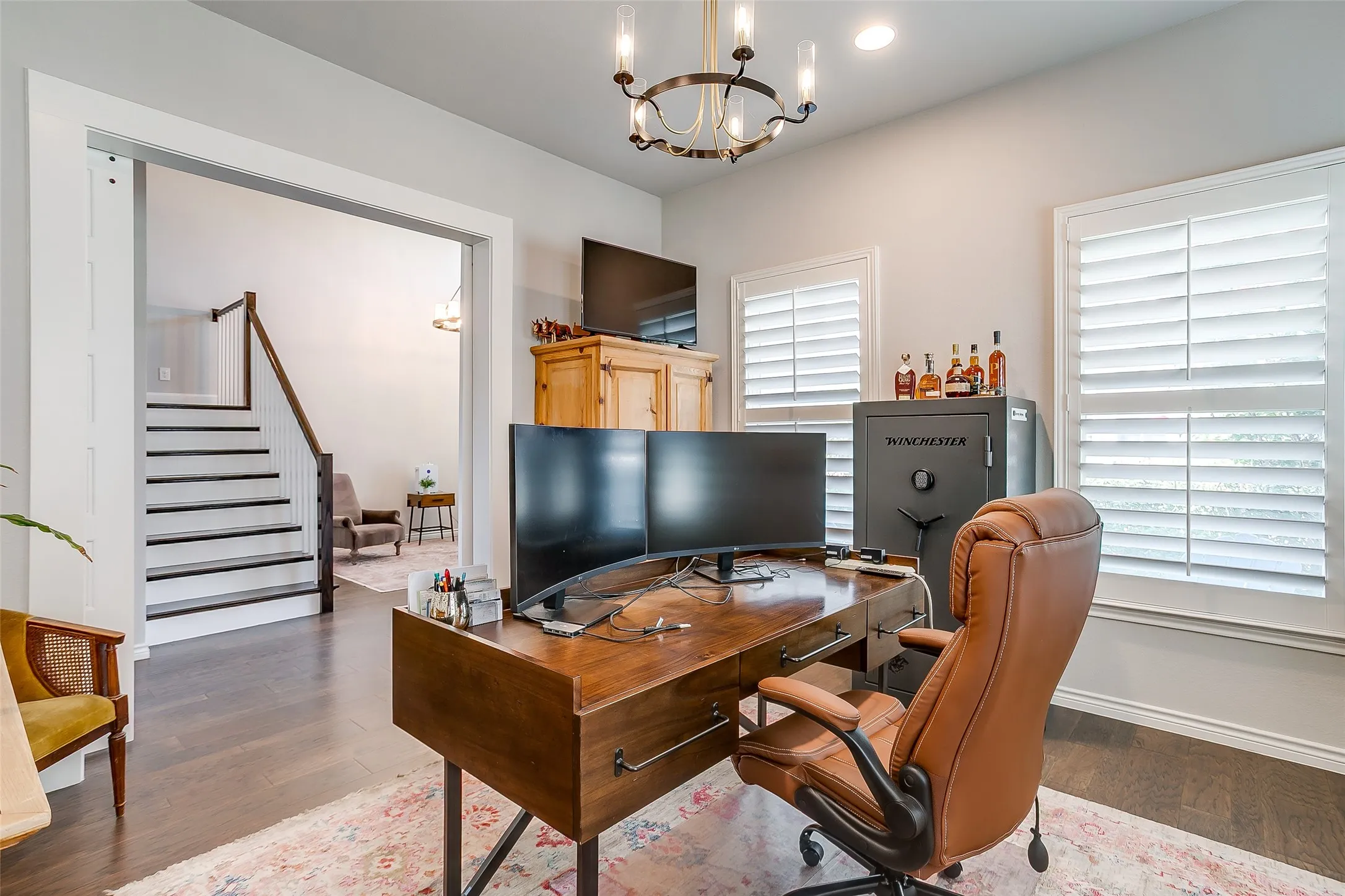 Interior space featuring dark wood-finish flooring, white walls, and a chandelier with clear glass shades