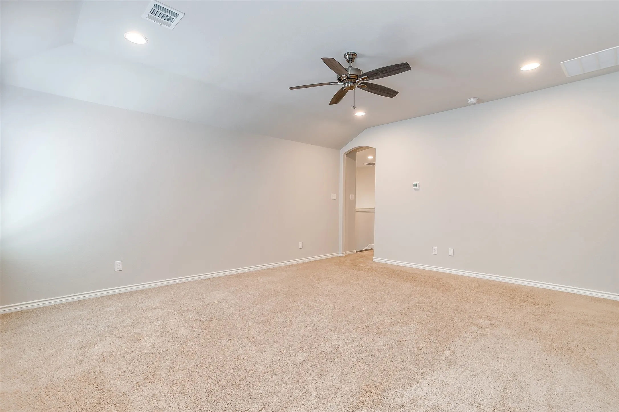 Spacious room featuring plush carpet, vaulted ceiling, recessed lighting, and a ceiling fan with integrated light