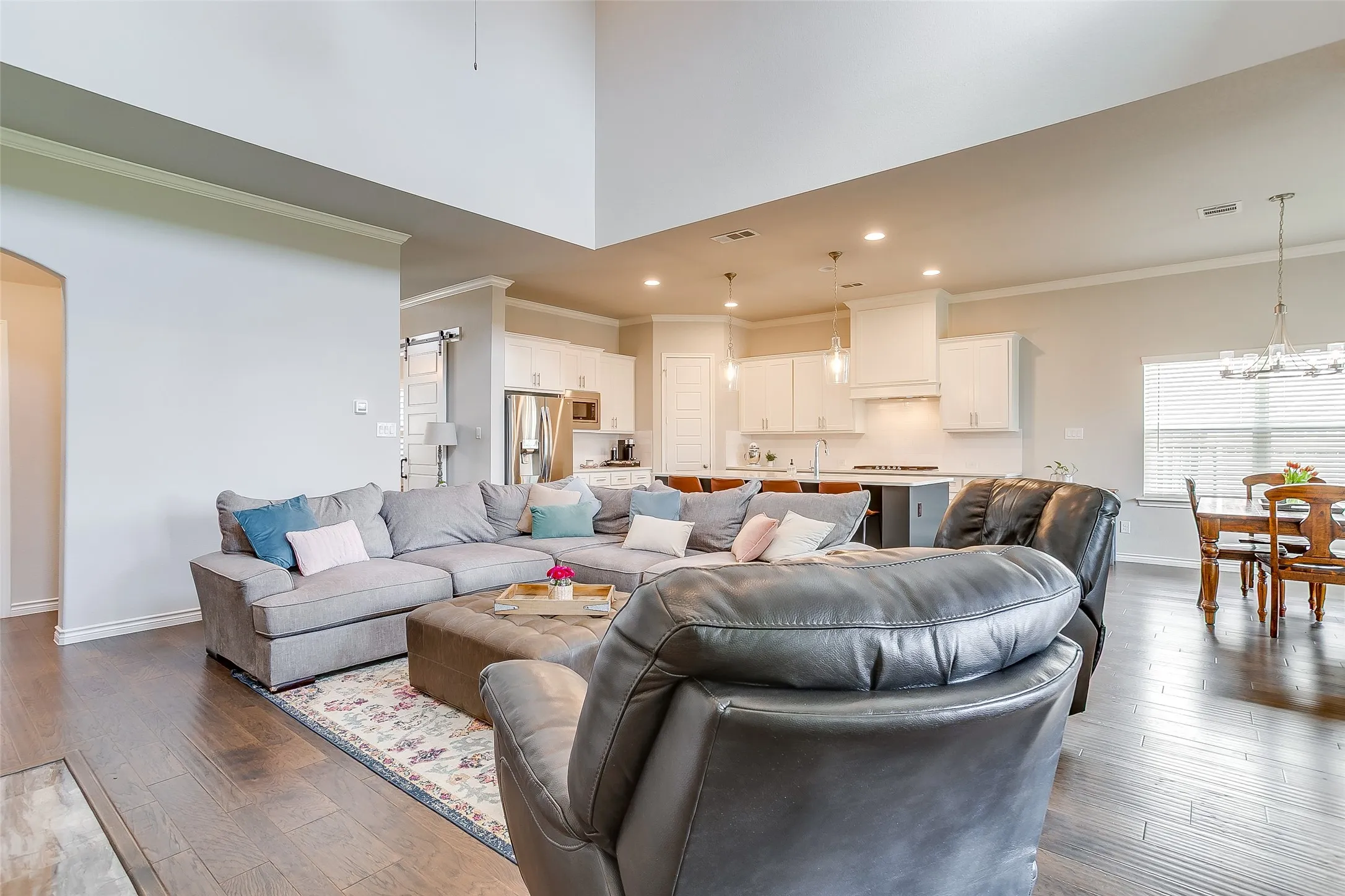 Spacious open-concept living area featuring wood-finish flooring and high ceilings
