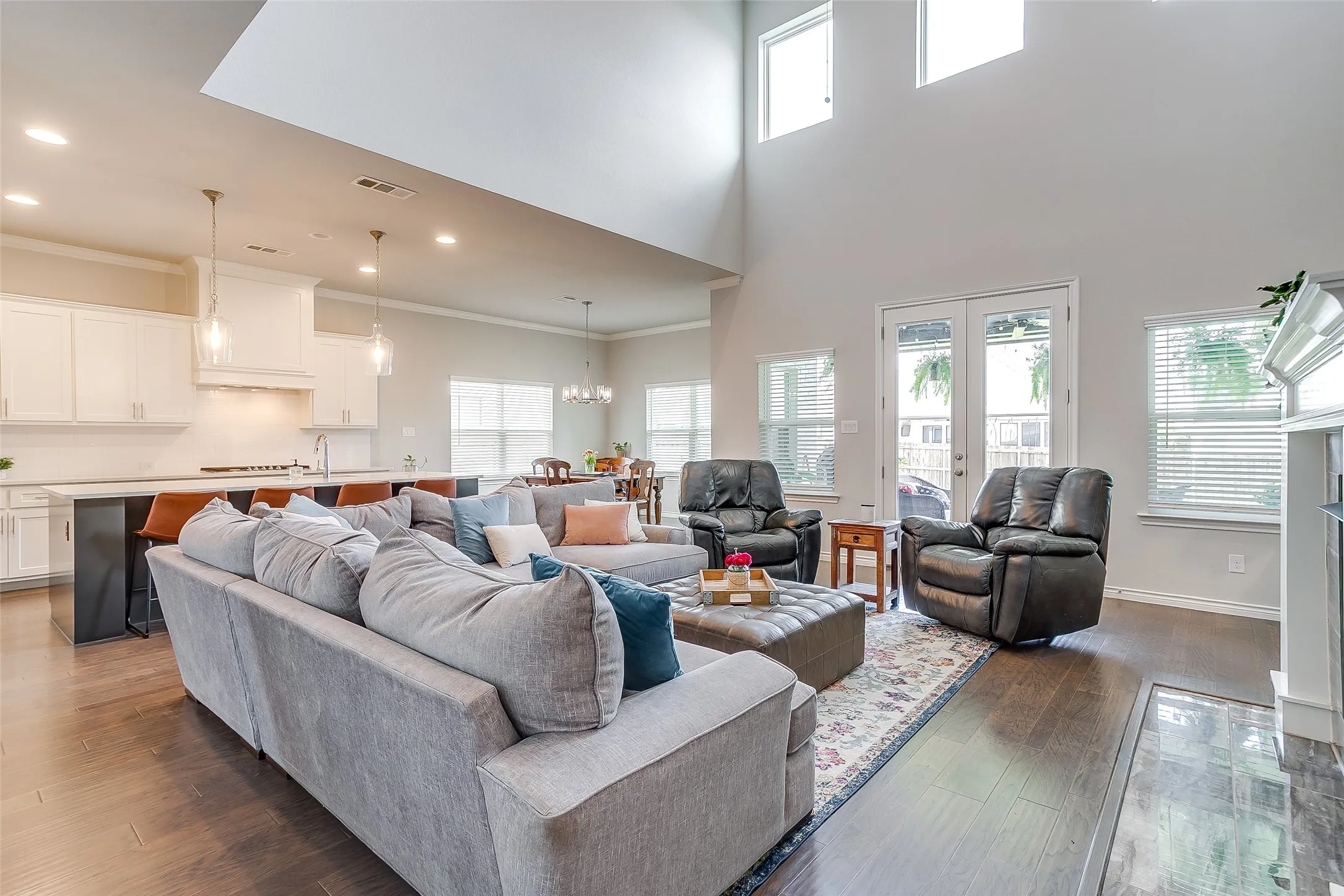 Open-concept living space featuring high ceilings, wood-finish flooring, and a fireplace with a white mantel