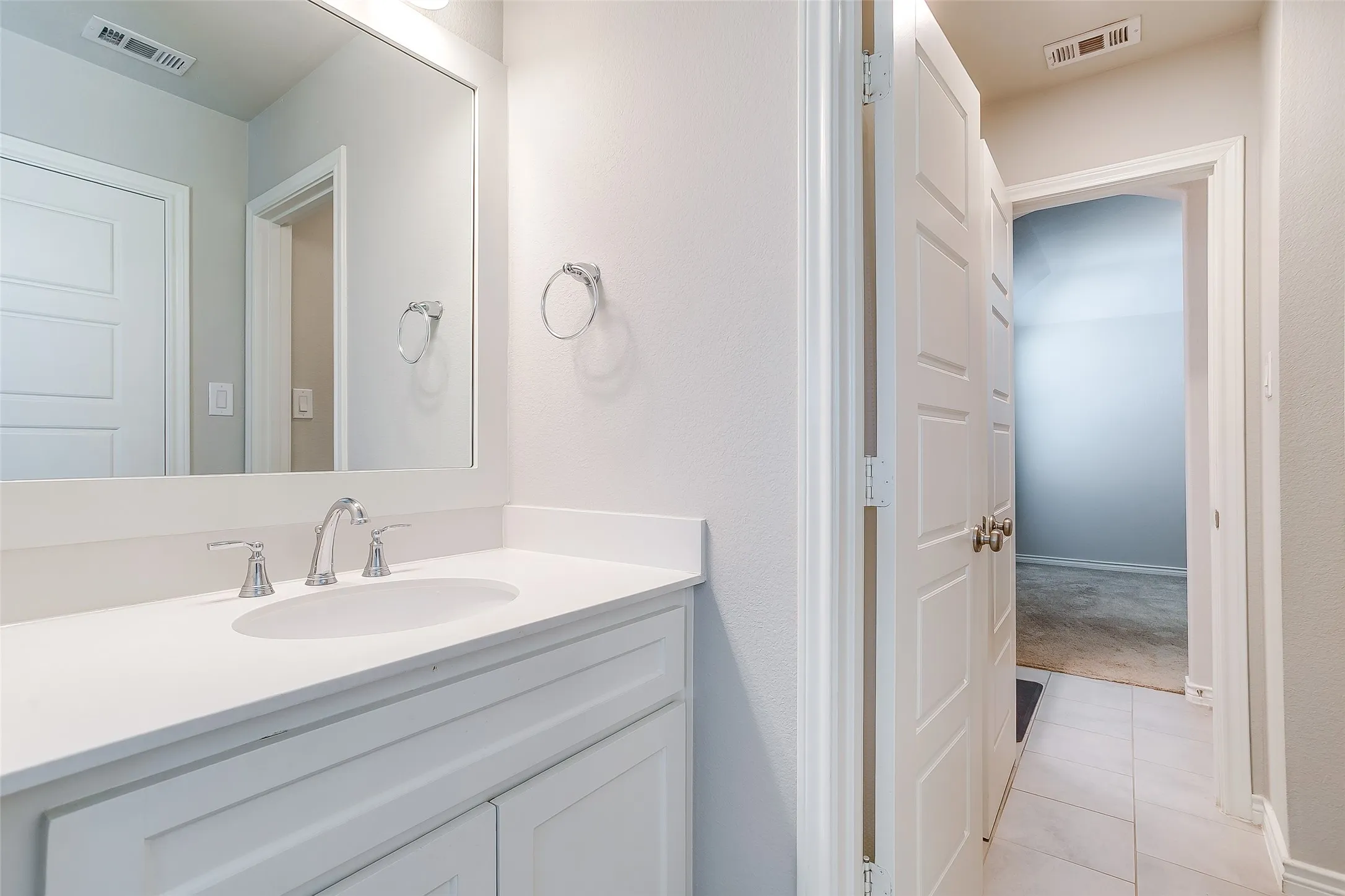 Bathroom vanity featuring a white countertop, undermount sink, and chrome faucet