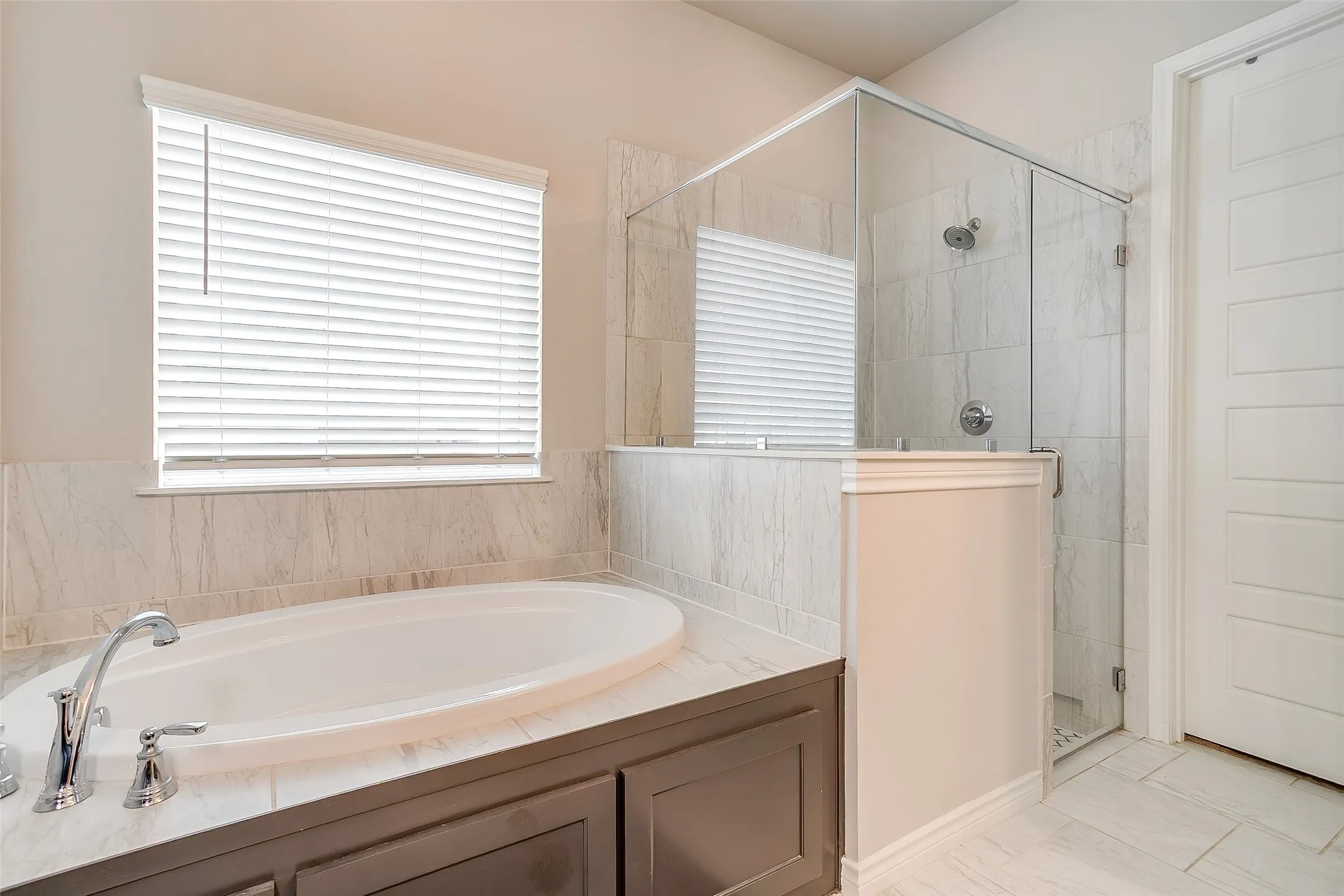 Soaking tub with chrome fixtures, surrounded by large format tile