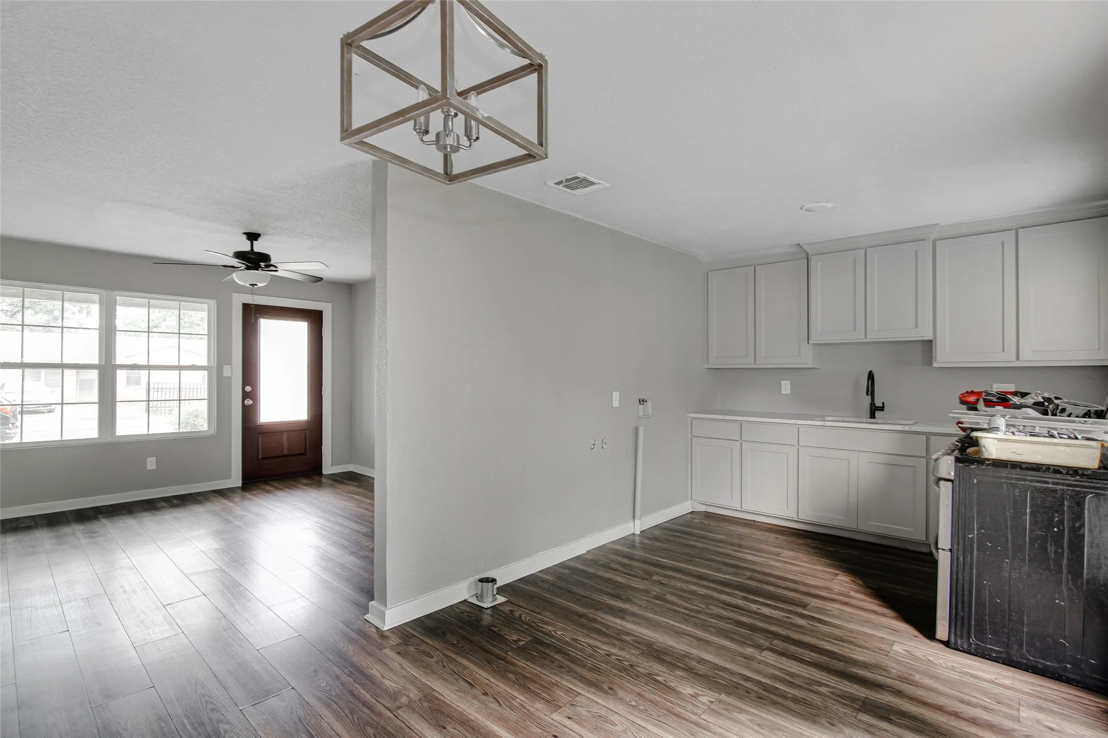 Open-concept living space featuring wood-finish flooring, a contemporary ceiling fan, and a light-filled entry door
