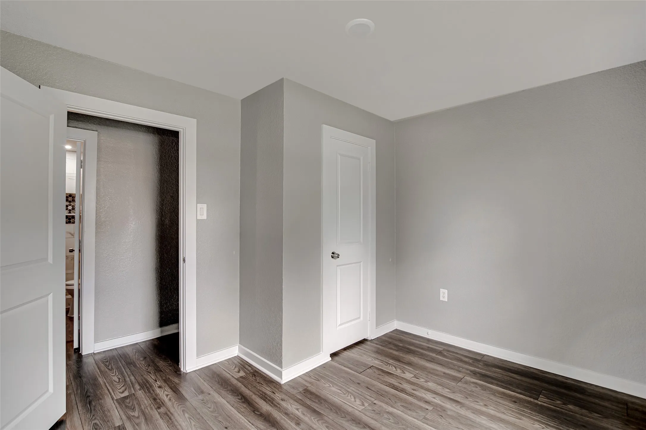 Interior room featuring wood-finish flooring, light grey painted walls, and white trim