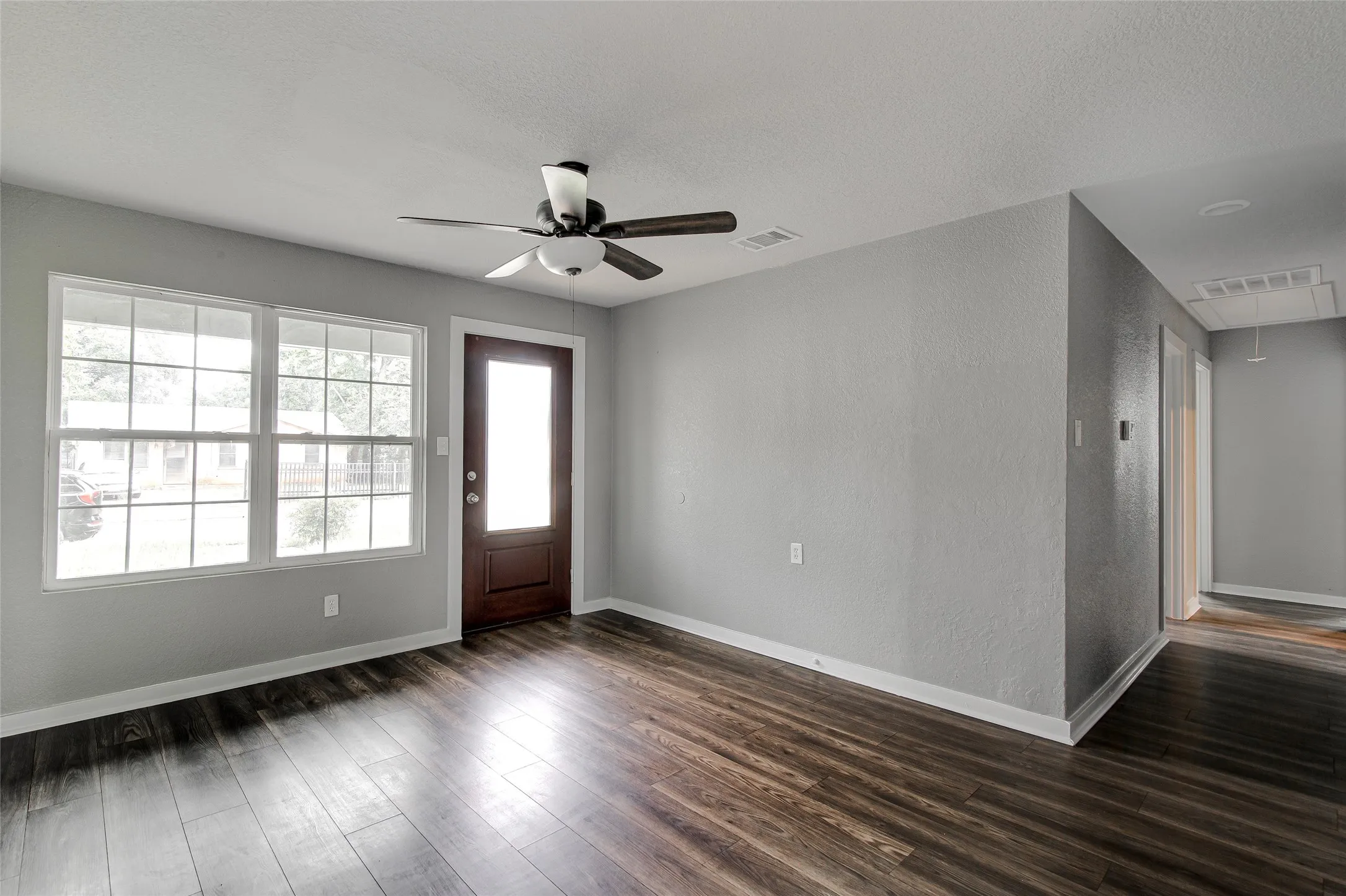 Spacious room featuring wood-finish flooring, light gray walls, and white trim