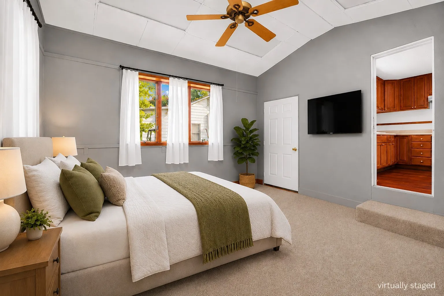 Carpeted room featuring a vaulted ceiling with a ceiling fan, three windows with wood frames, and a built-in cabinet area with wood-finish flooring