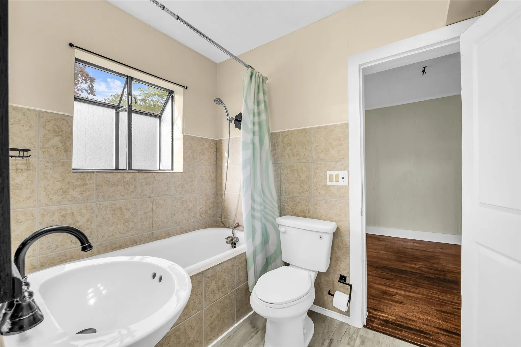 Bathroom featuring a pedestal sink, framed mirror, and a bathtub with tile surround