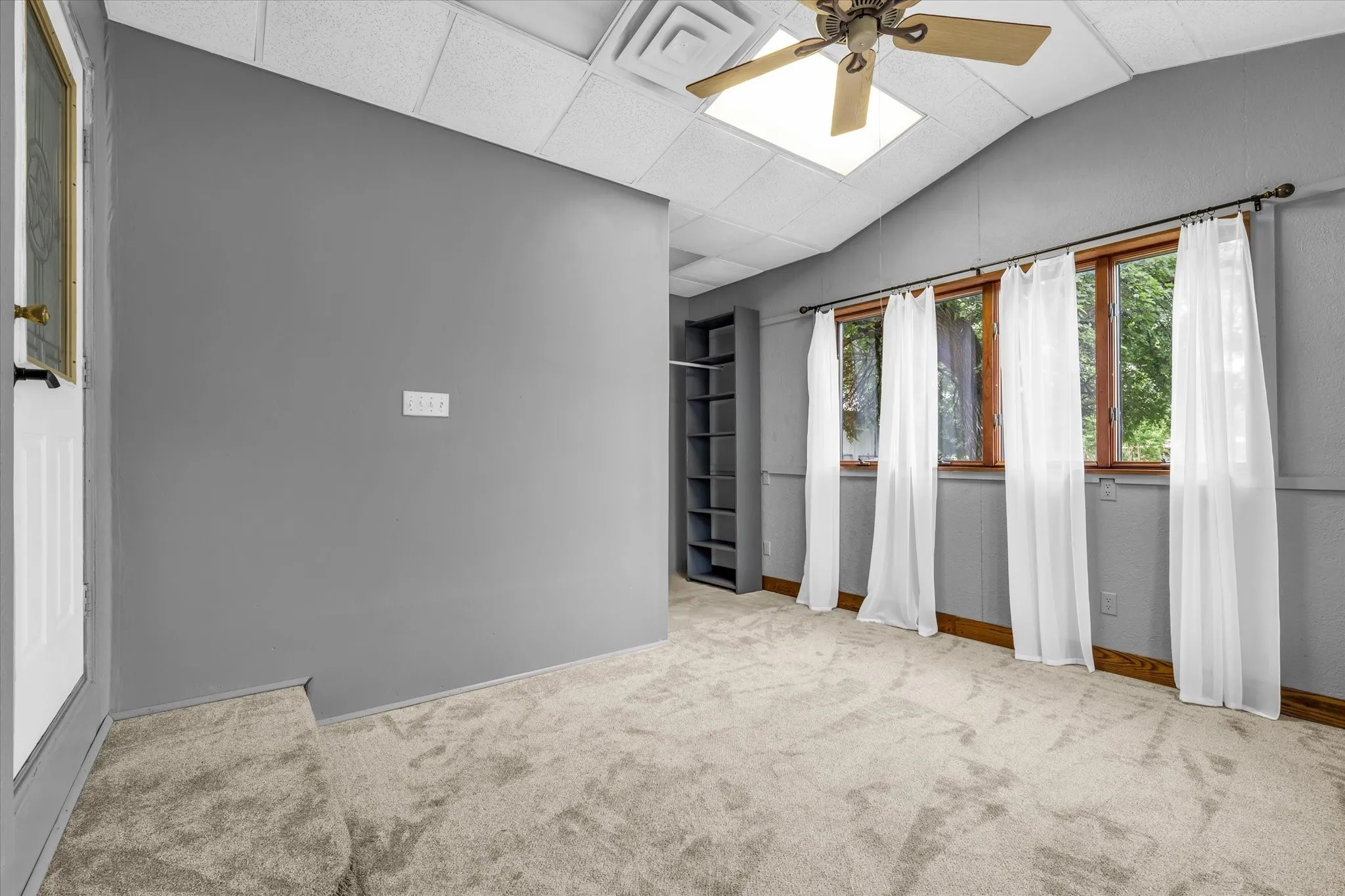 Spacious room featuring vaulted ceilings with a ceiling fan, recessed lighting, and drop-panel ceiling tiles