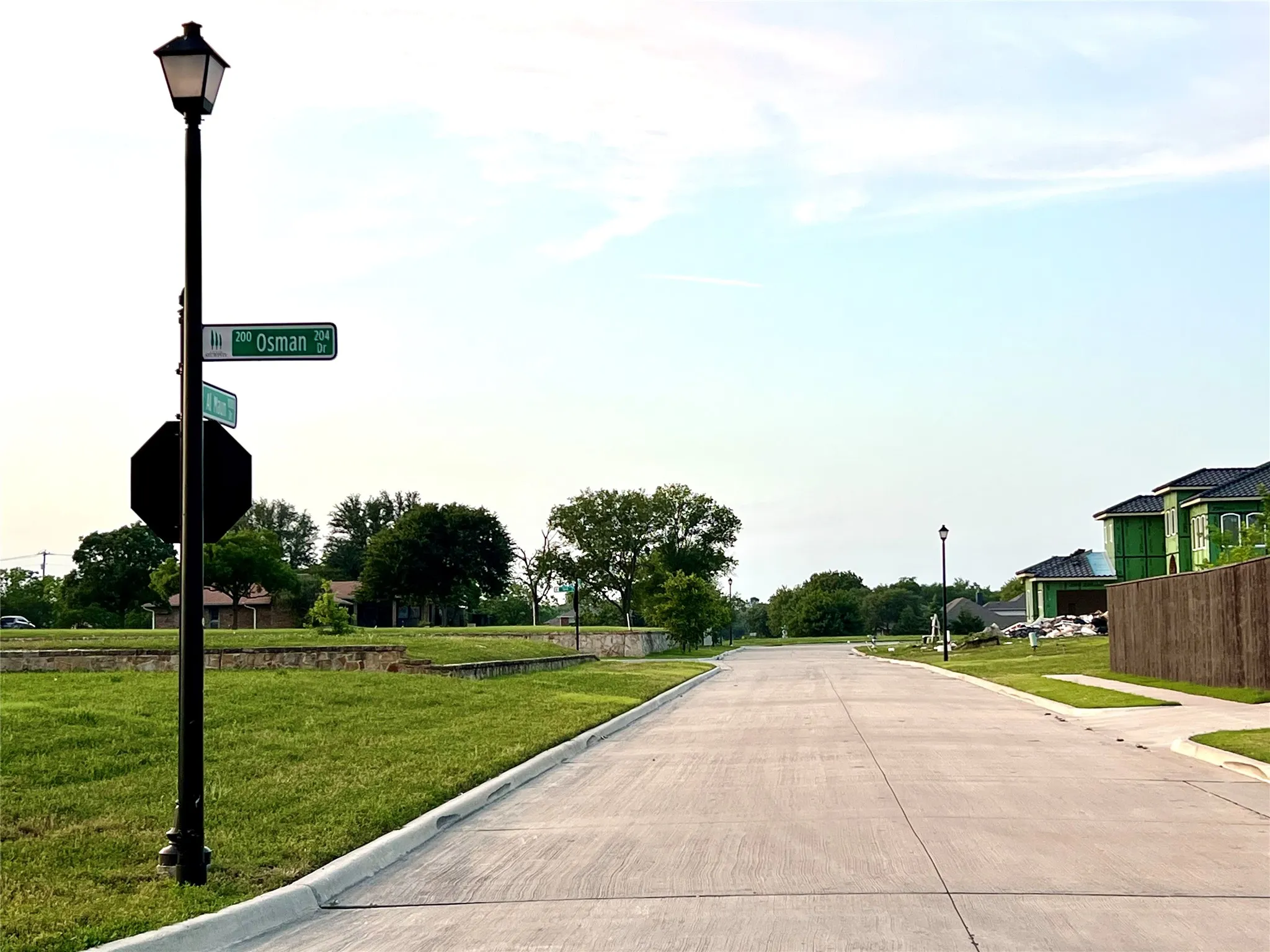 View of concrete road featuring curbs, street lights, and traffic signs