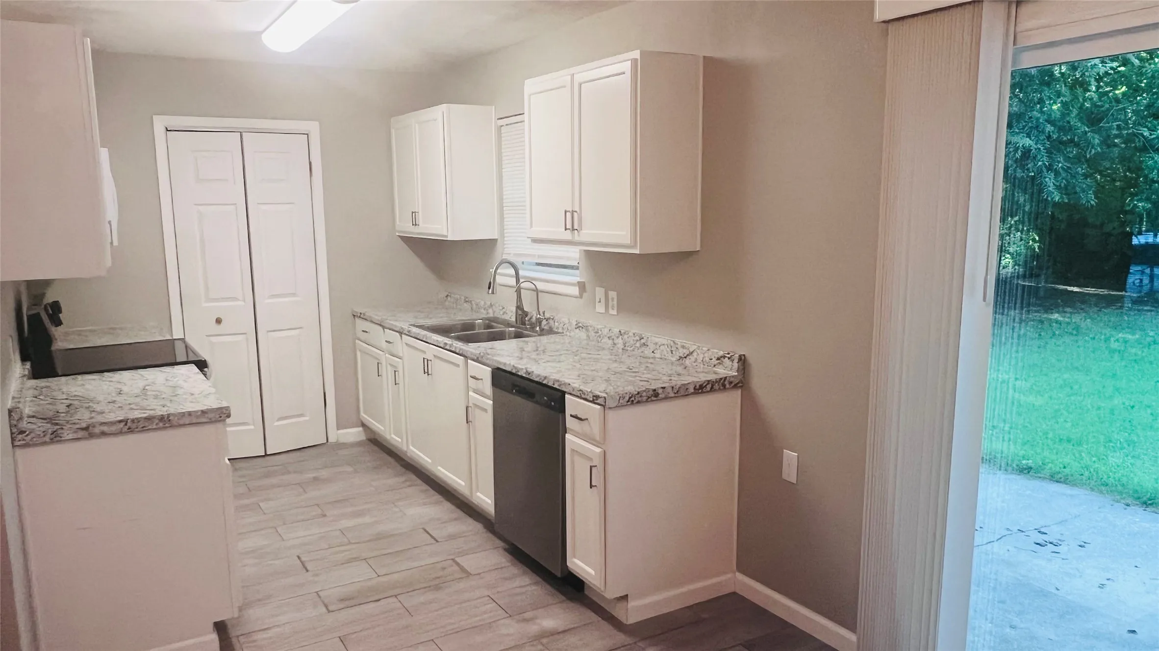 Kitchen featuring white shaker cabinetry, speckled countertops, stainless steel appliances, and wood-finish flooring