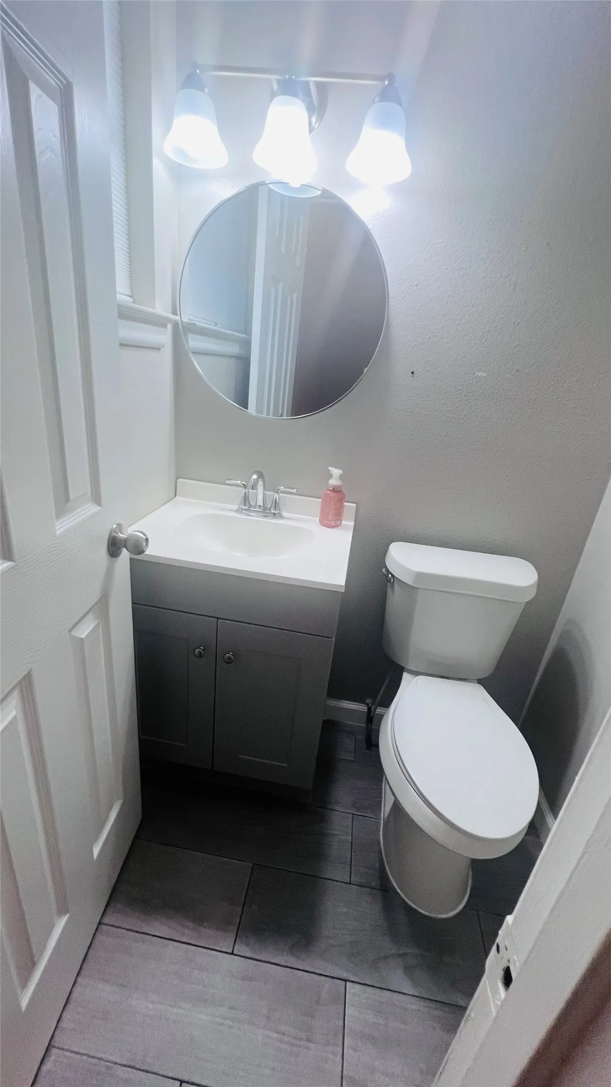 Bathroom featuring a single-sink vanity with white countertop, chrome faucet, and gray cabinetry