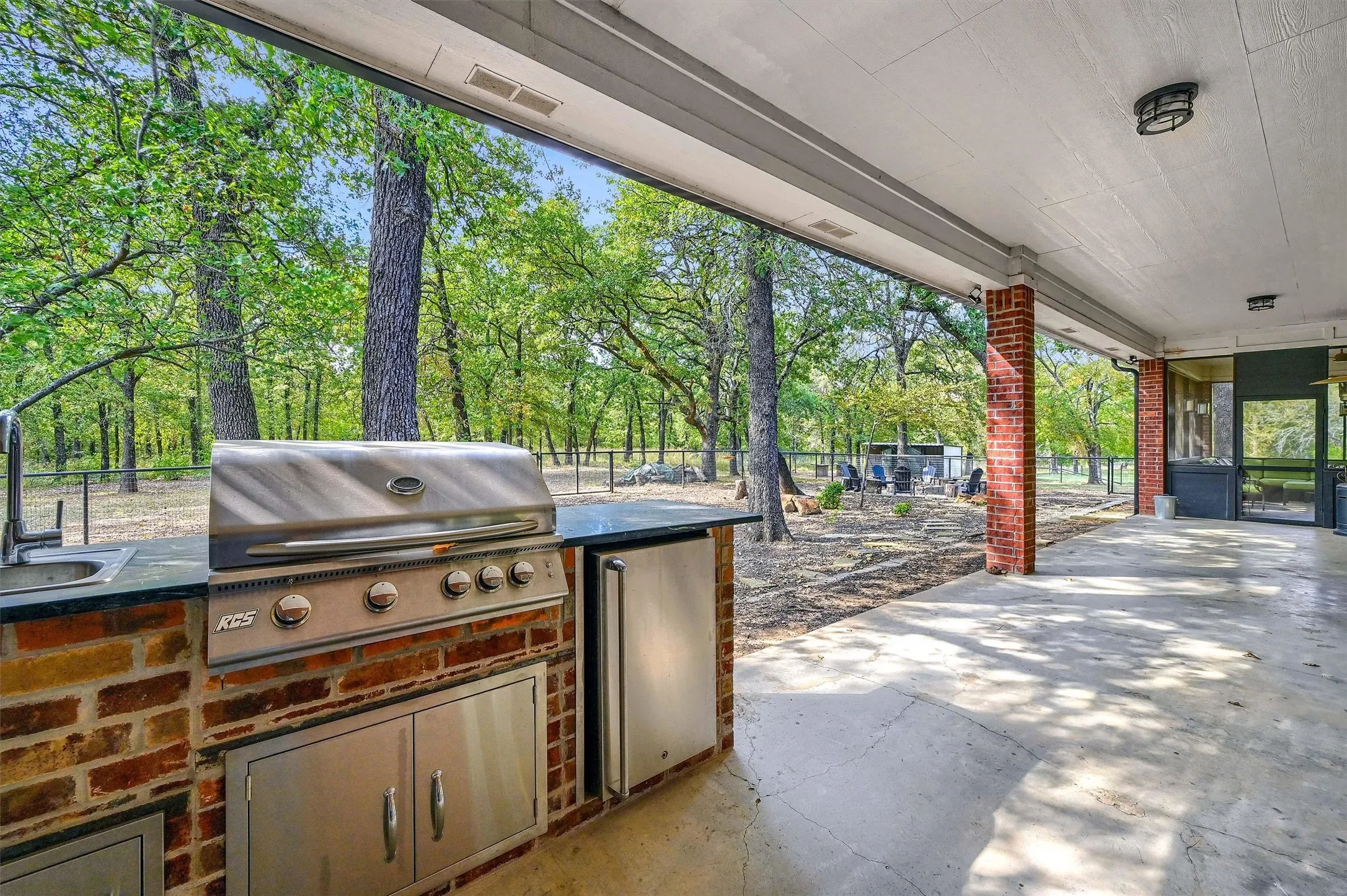 Outdoor kitchen under the covered patio, complete with a grill and refrigerator.