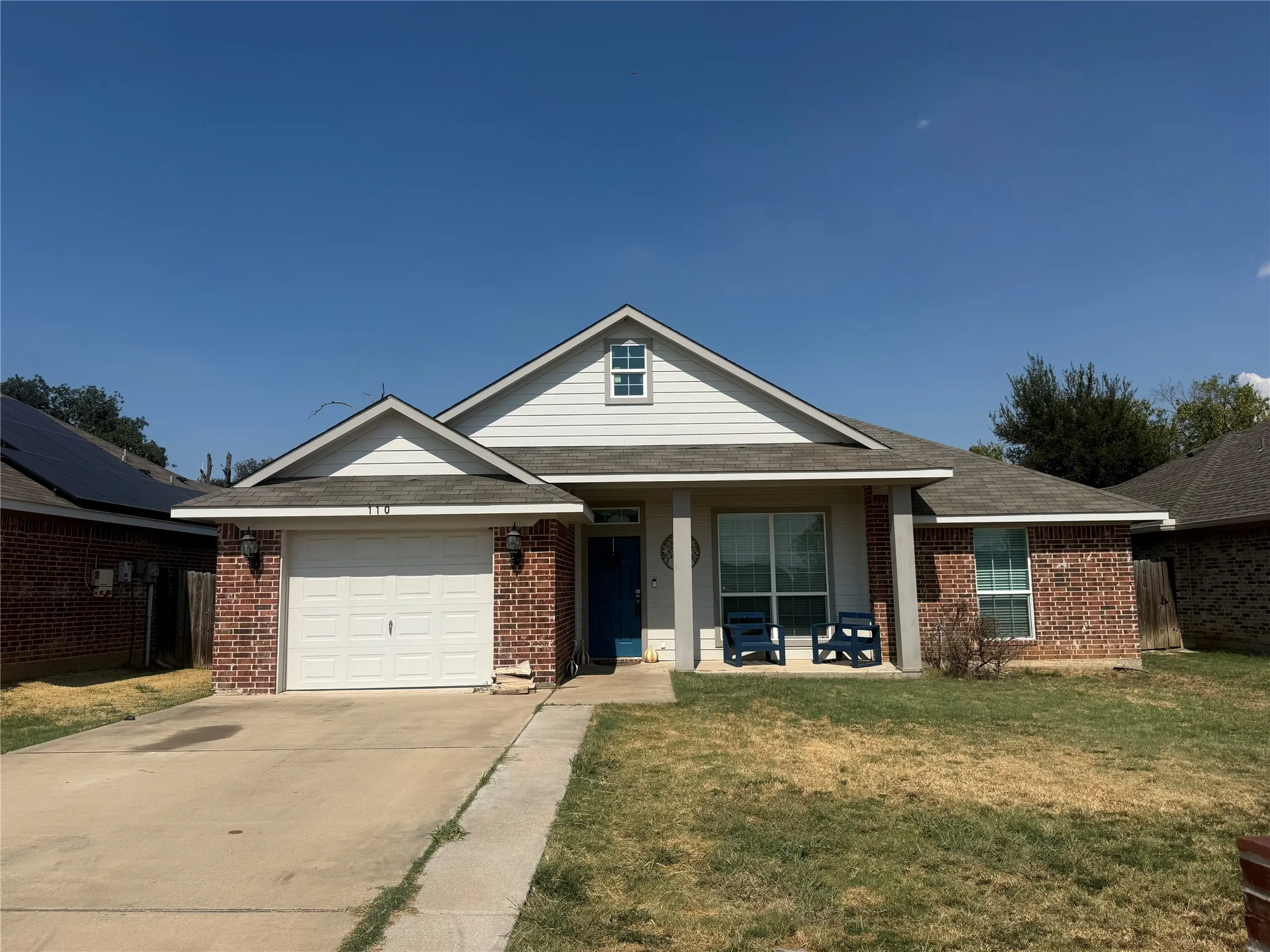Brick and siding exterior with a gabled roofline, featuring an attached garage and a covered front porch