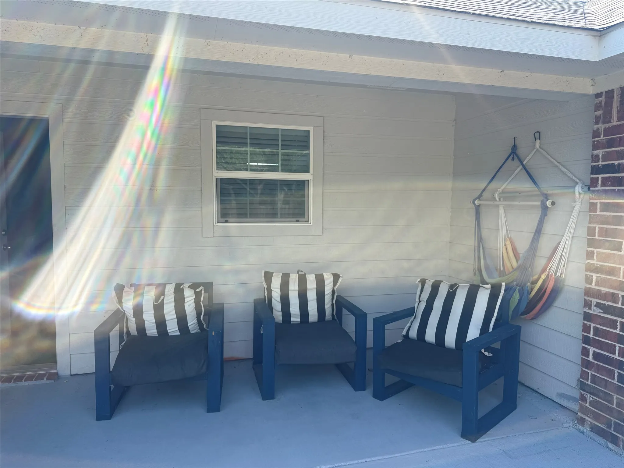 Covered patio featuring a painted concrete surface and a partial brick exterior wall
