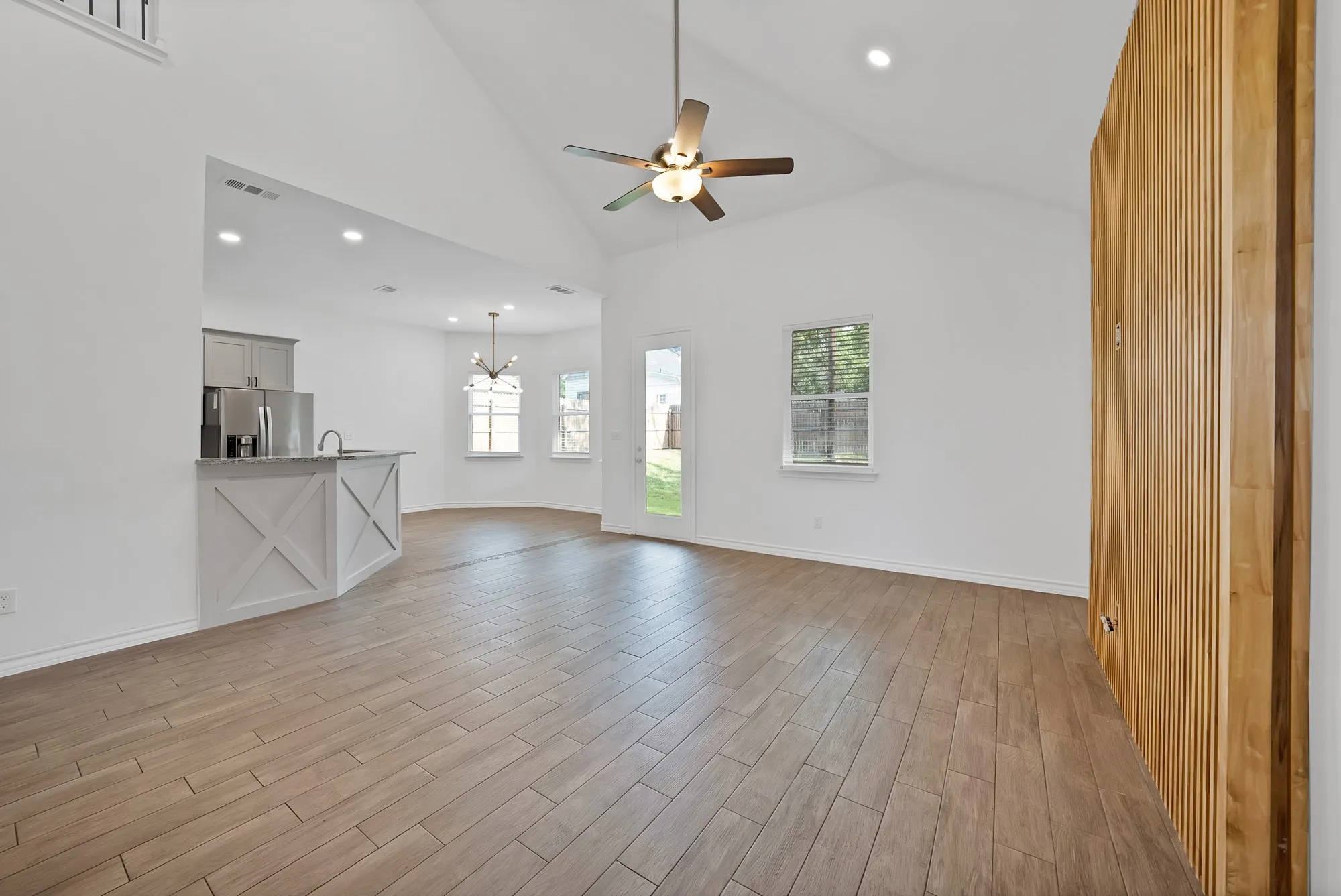Open-concept living space with vaulted ceilings and wood-finish tile flooring