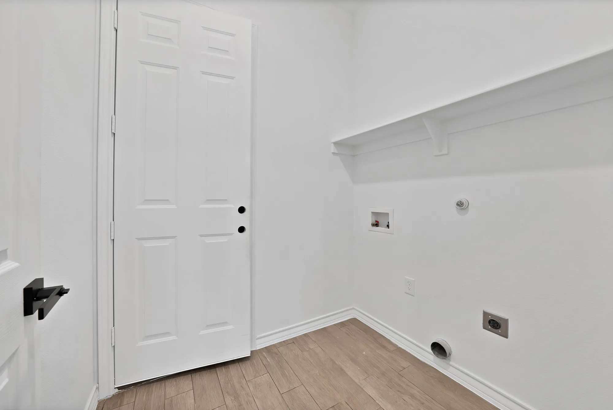 Utility space featuring wood-finish flooring, white walls, and a built-in shelf