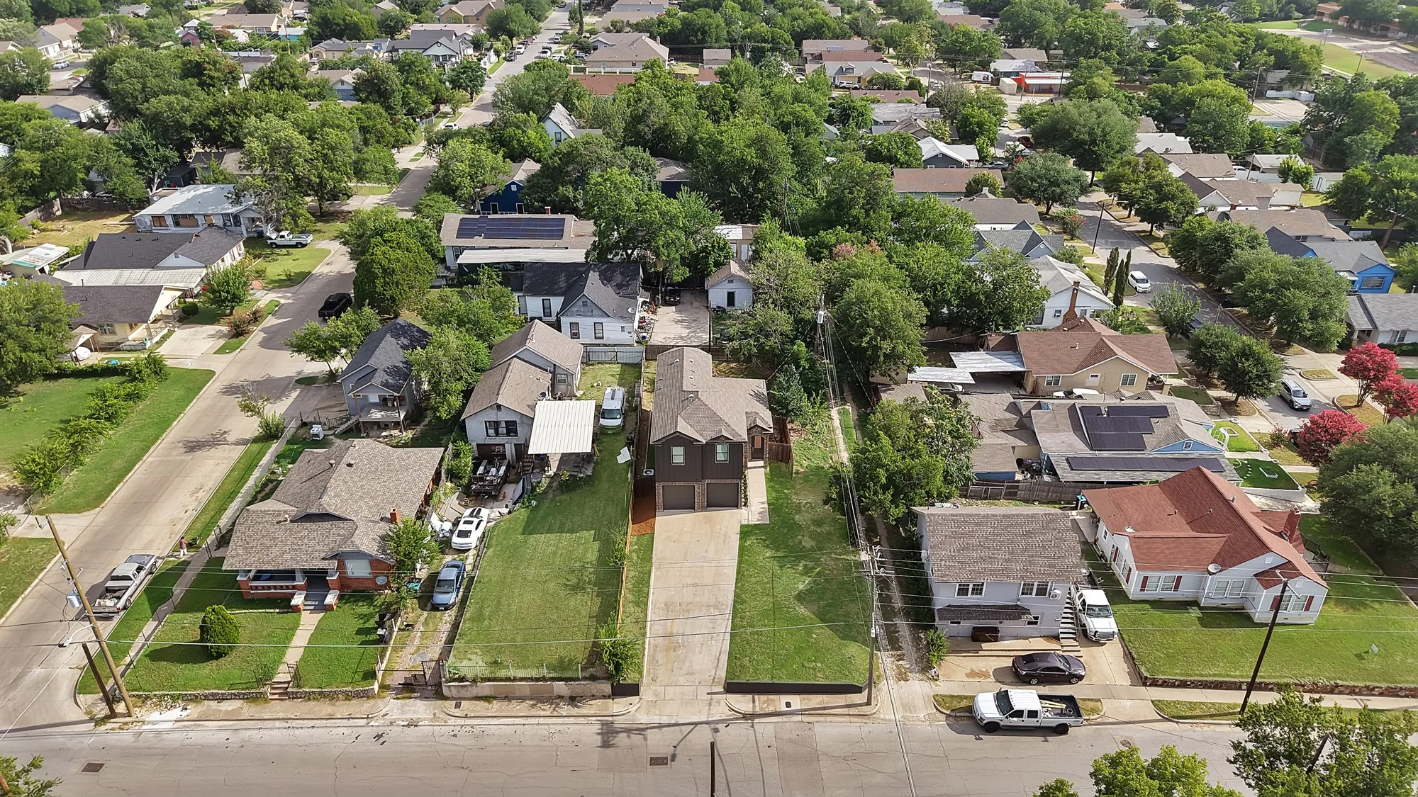Aerial perspective showcasing a residential street with diverse architectural styles, mature trees, and individual properties