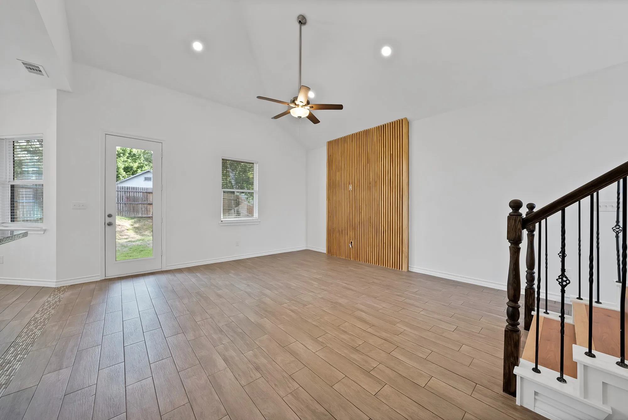 Open-concept living space with vaulted ceilings and wood-finish tile flooring