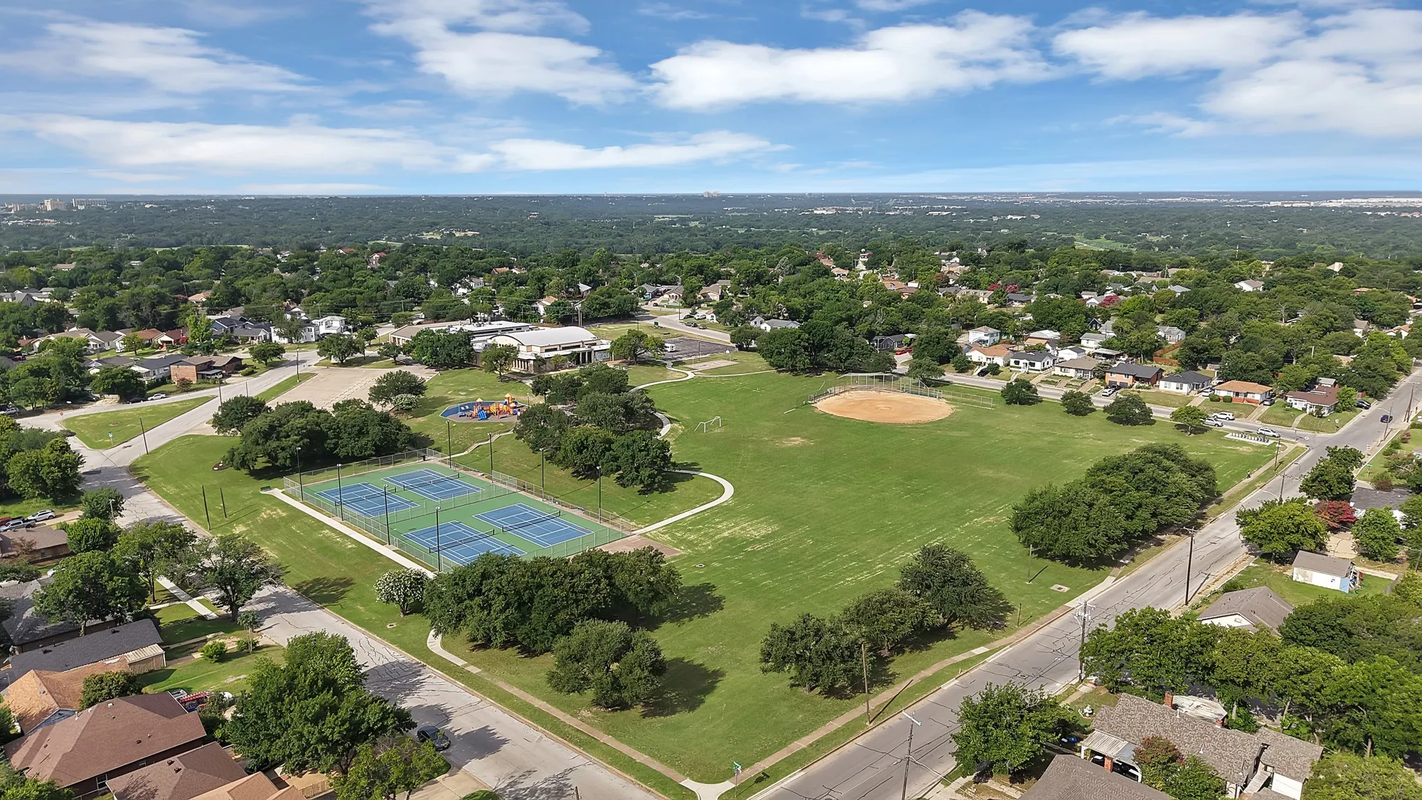 Aerial perspective of a verdant neighborhood park featuring multiple recreational amenities