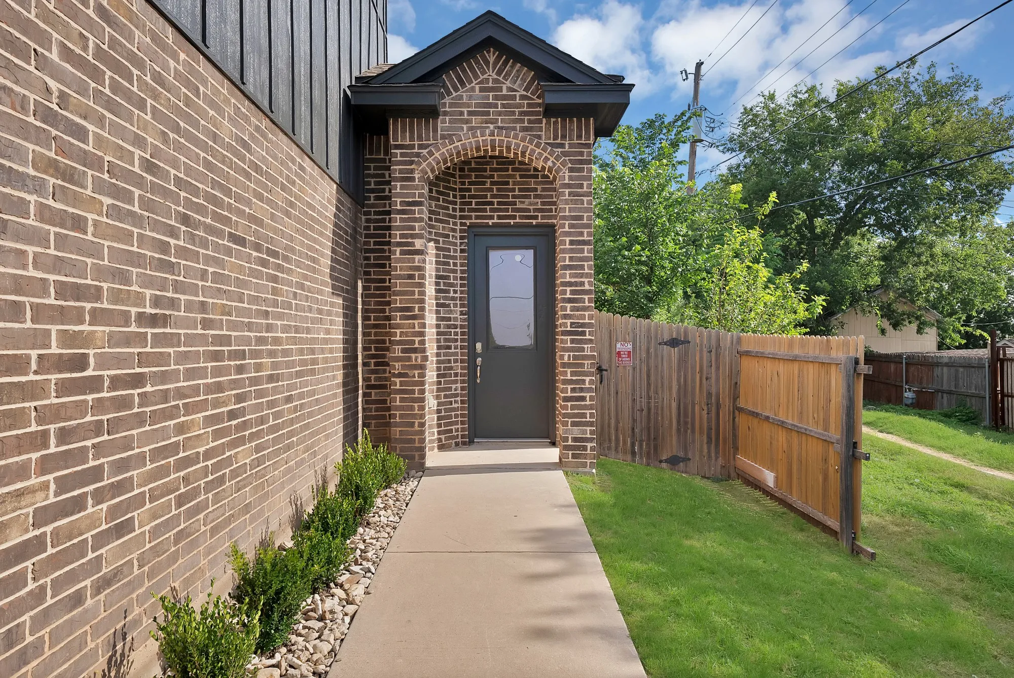 Brick exterior featuring a covered entry with an arched brick detail
