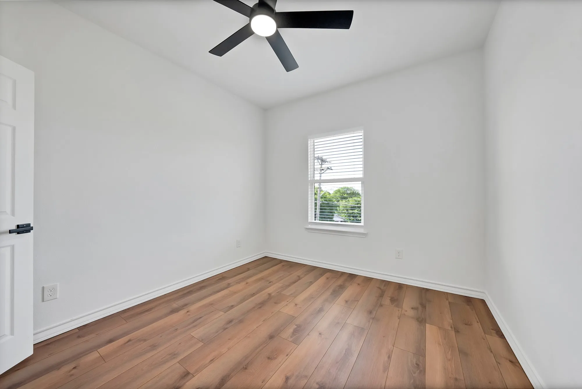 Interior room featuring wood-finish flooring, white walls, and a window with blinds