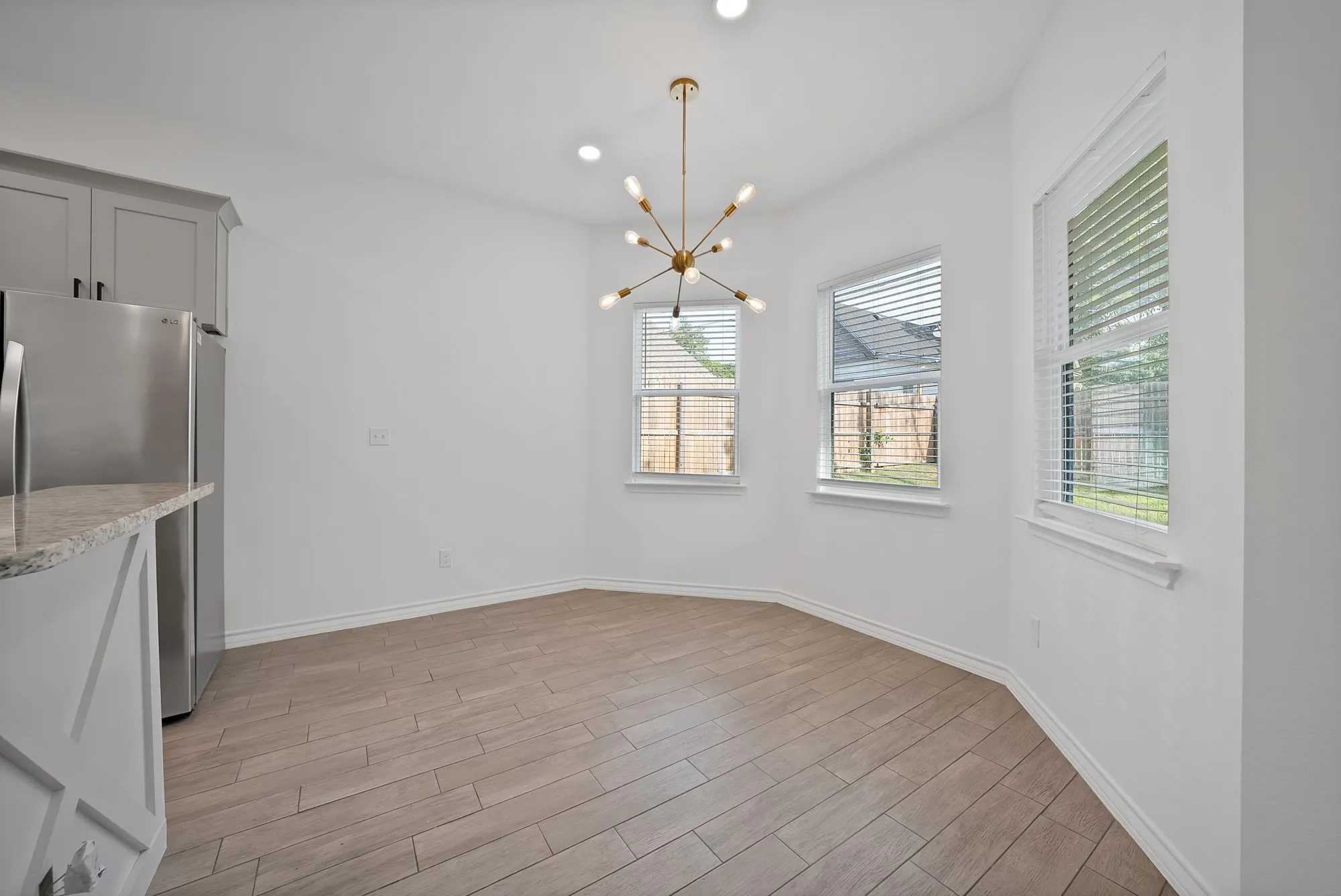 Dining area featuring wood-finish flooring, a modern sputnik chandelier, and three windows with blinds