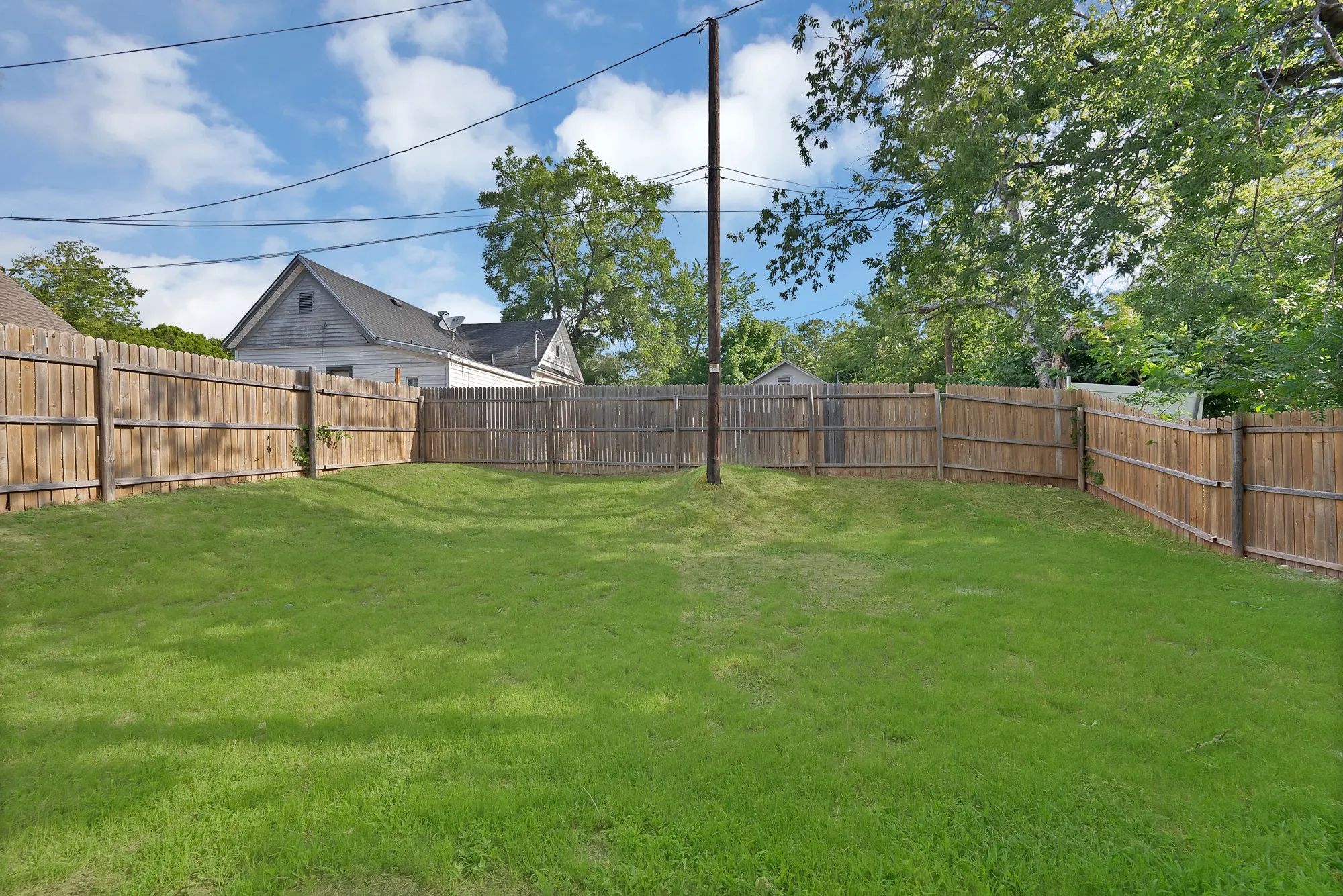 Expansive backyard featuring a lush lawn, complete wood privacy fencing, and mature perimeter trees