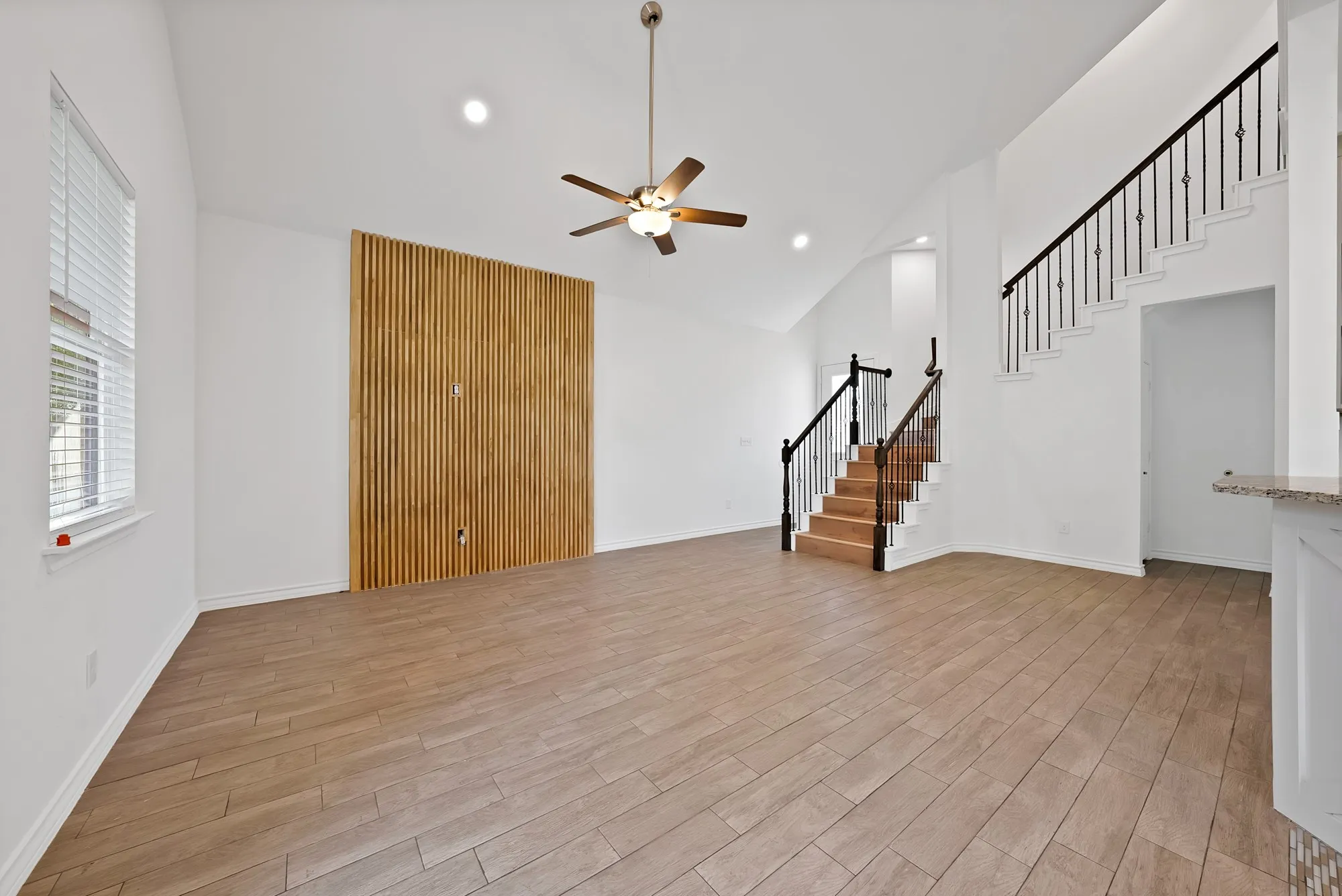 Open-concept living space with vaulted ceilings and wood-finish tile flooring