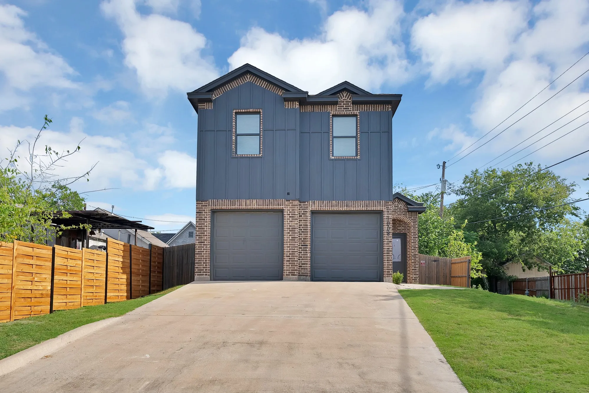Contemporary two-story exterior featuring a brick and vertical siding facade